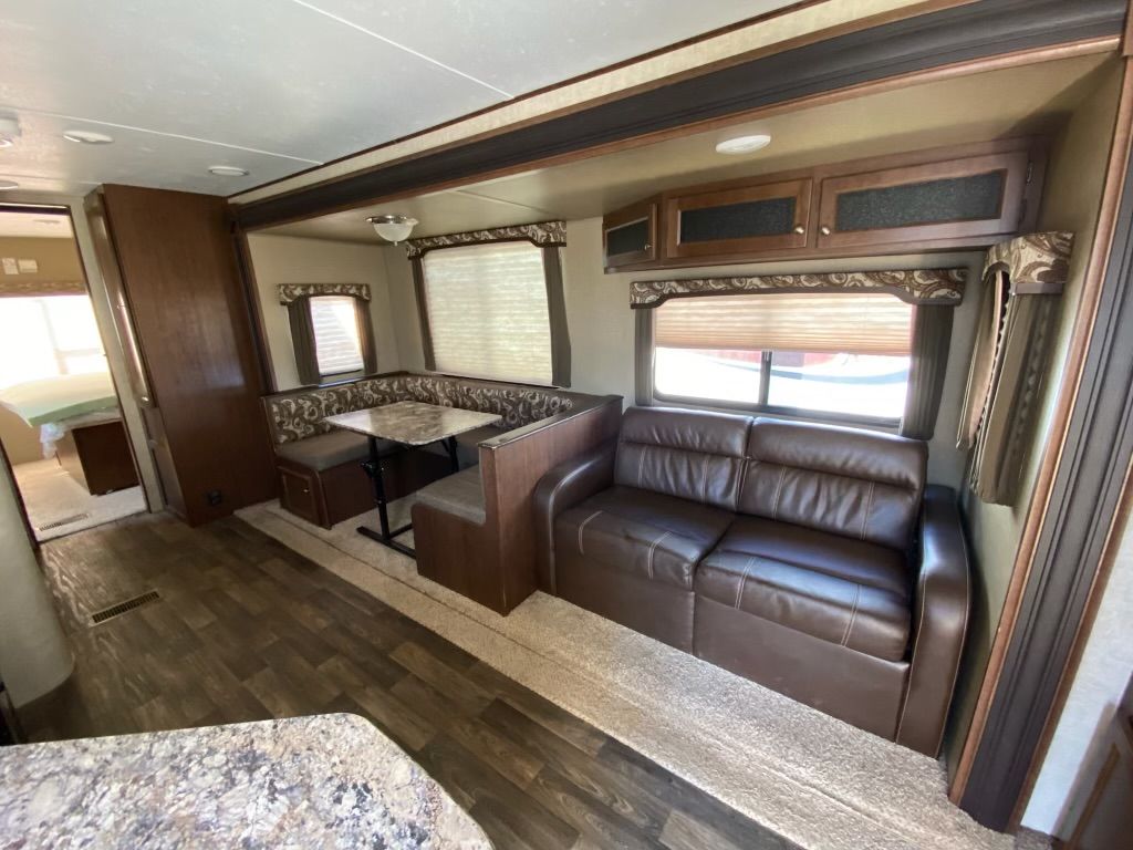A living room in a trailer with a couch , table and chairs.