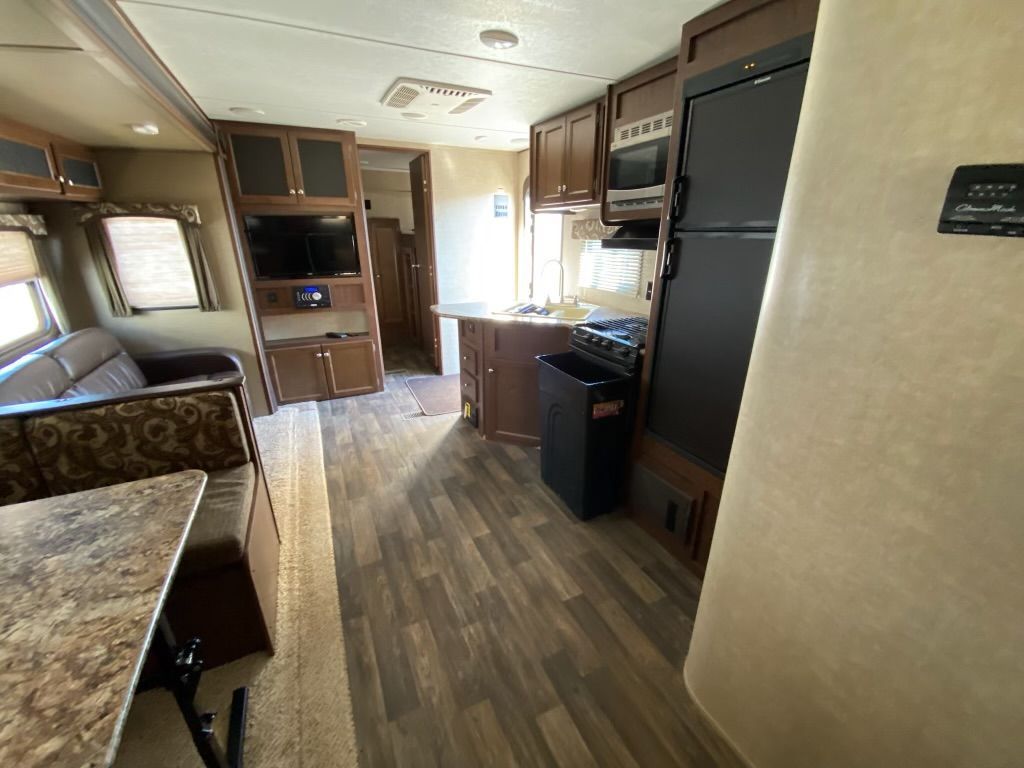 A rv with a couch , table , refrigerator , microwave and television.