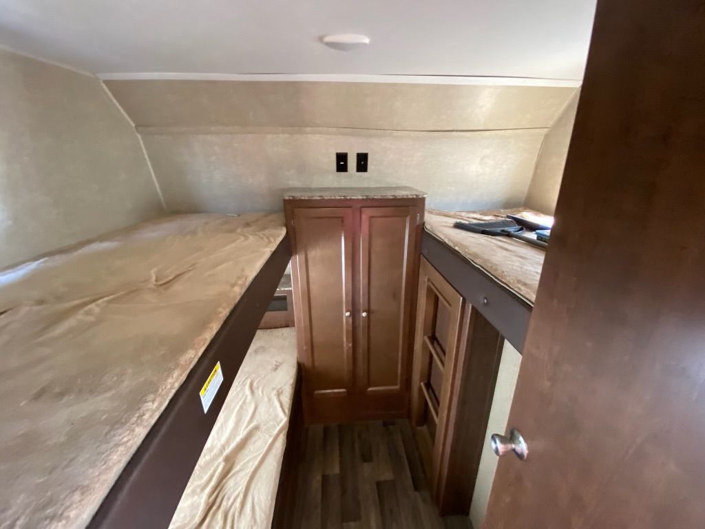 A bedroom in a trailer with two bunk beds and a door.