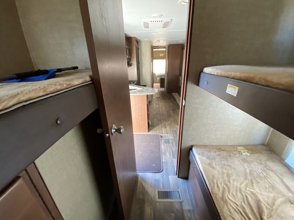 The inside of a rv with bunk beds and a kitchen.