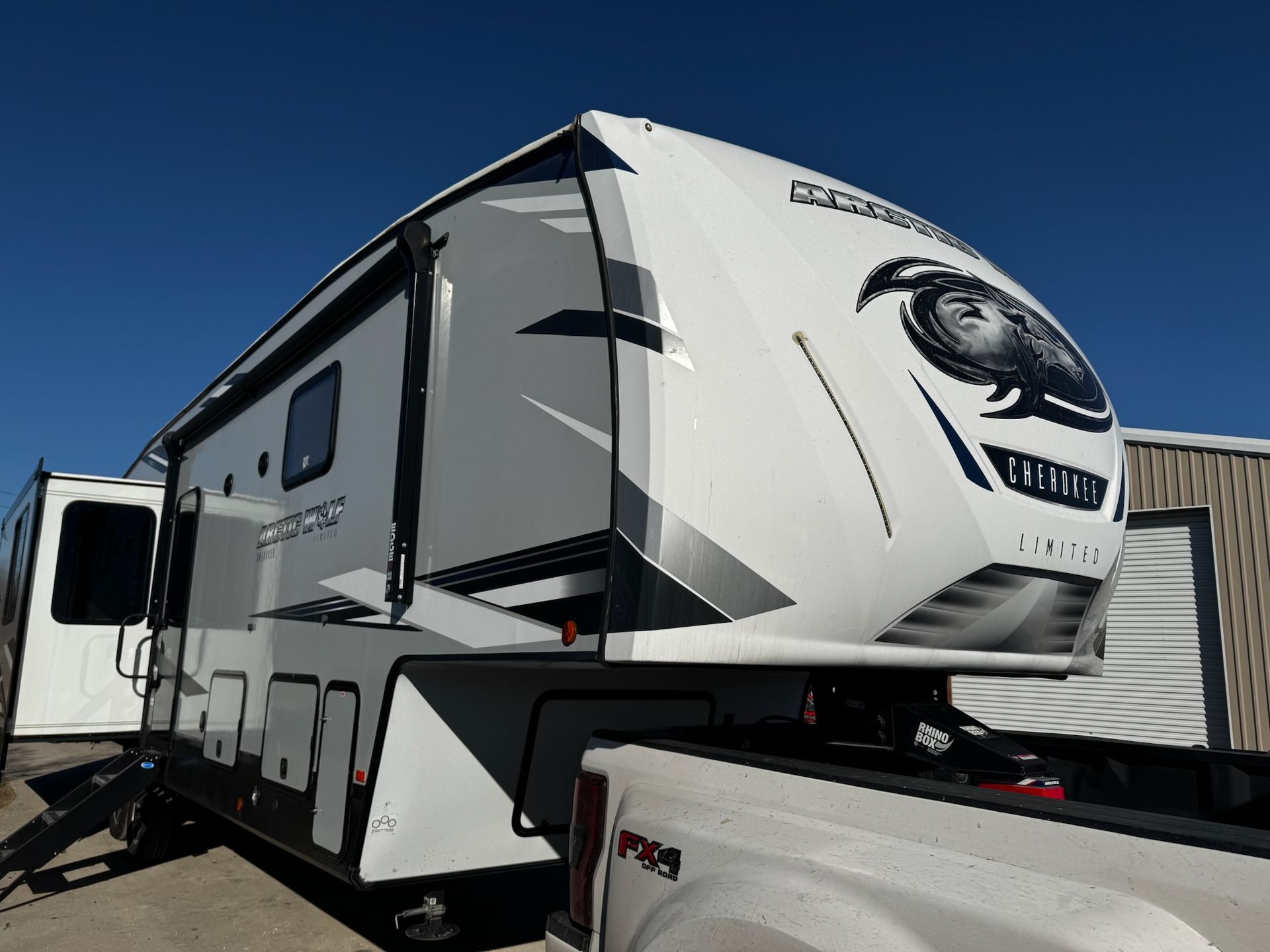 A white rv is parked next to a truck.