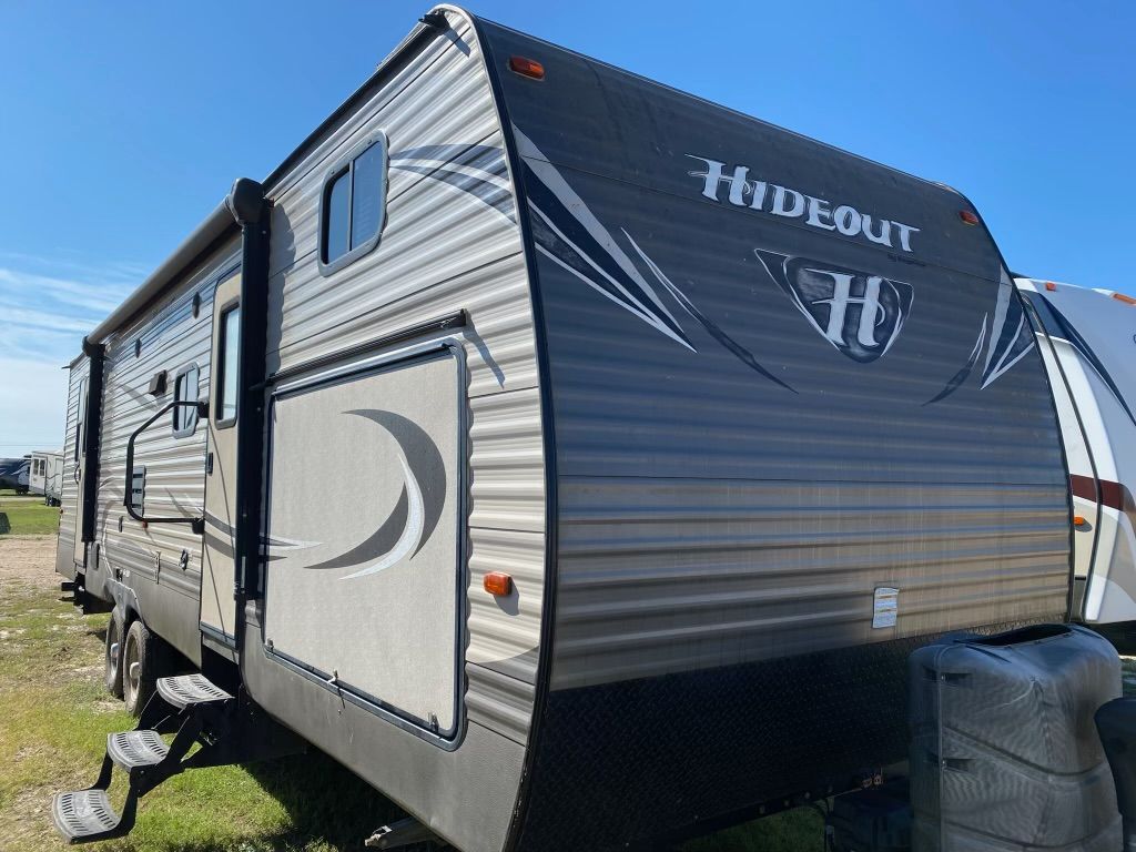 A rv is parked in the grass in a field.