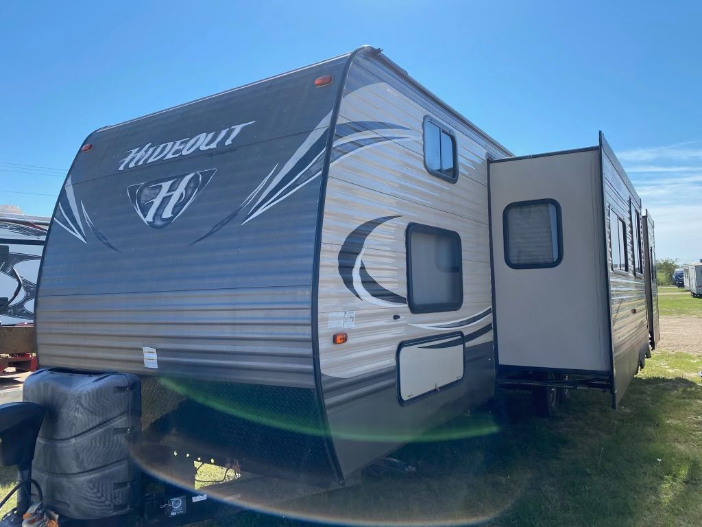 A rv is parked in a field on a sunny day.