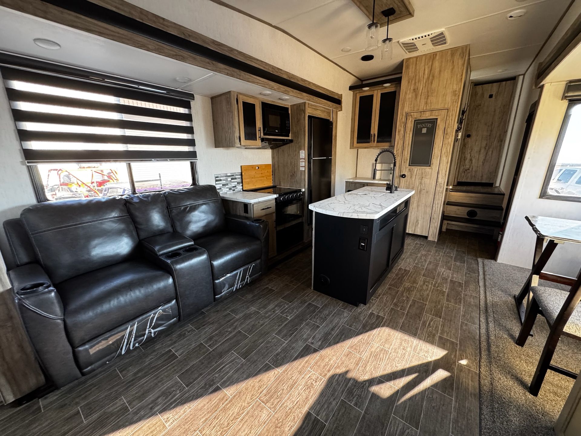 A living room with a couch , chairs , and a kitchen in a trailer.