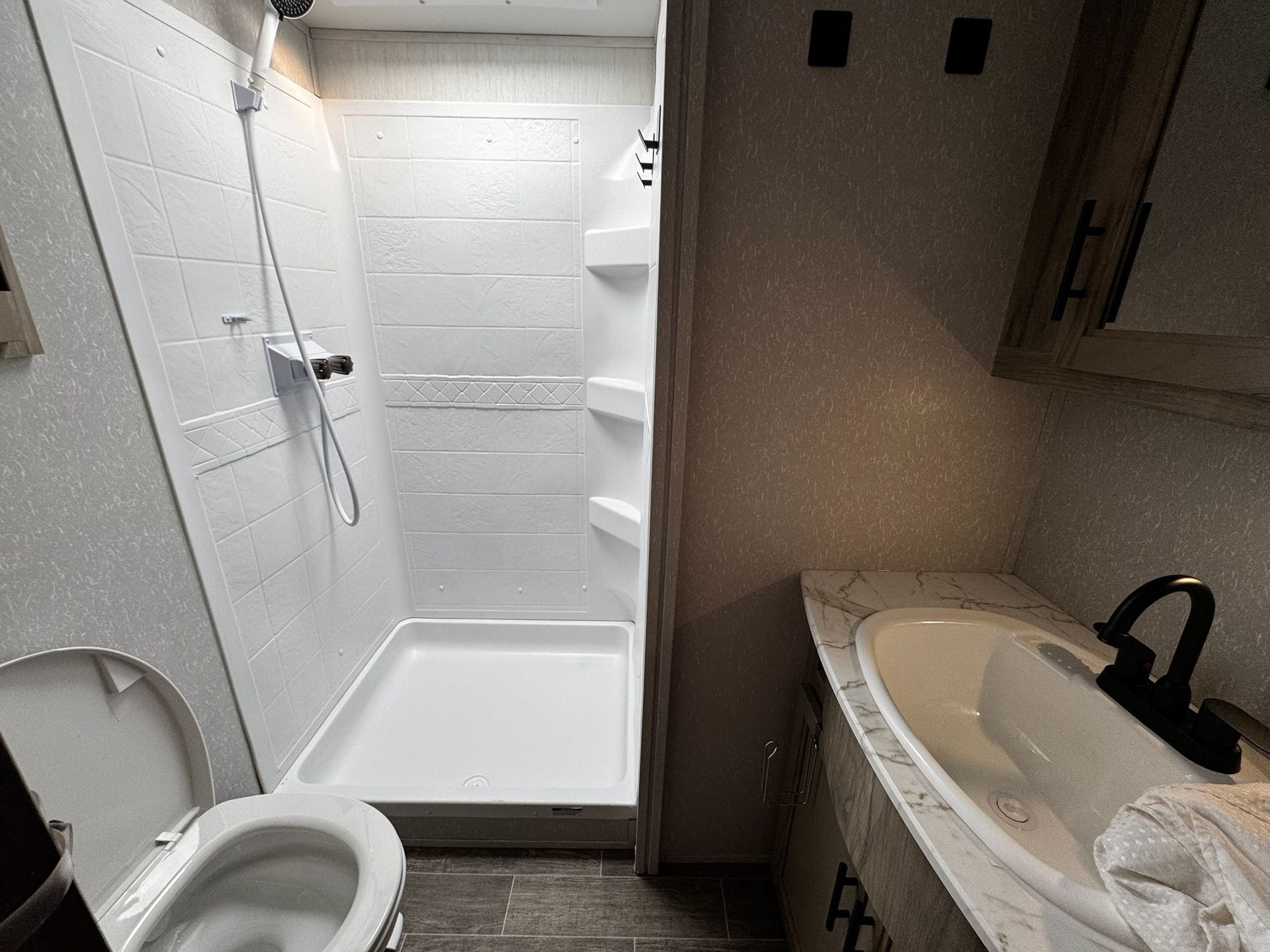 A bathroom with a toilet , sink and shower.