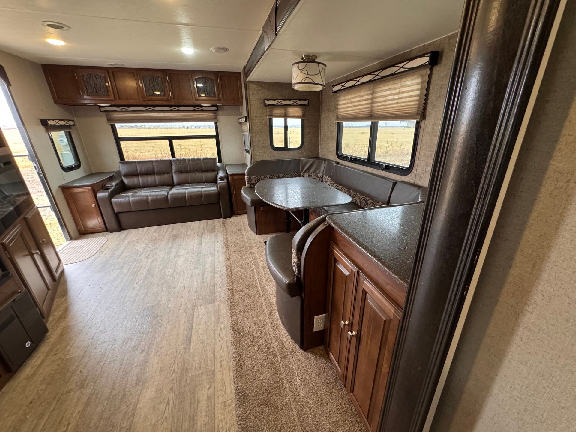 A living room in a trailer with a couch , table and chairs.