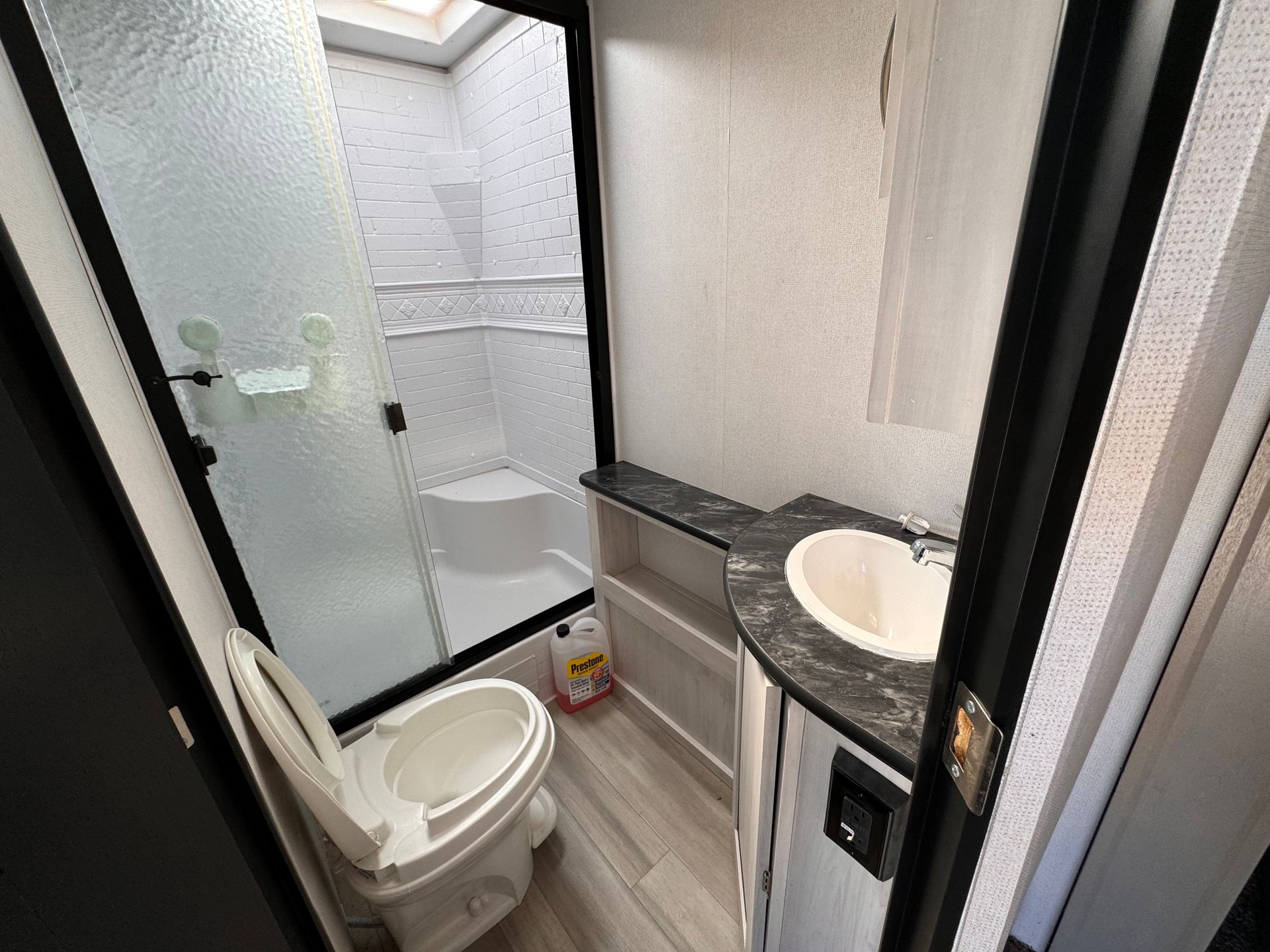 A bathroom with a toilet , sink and shower.