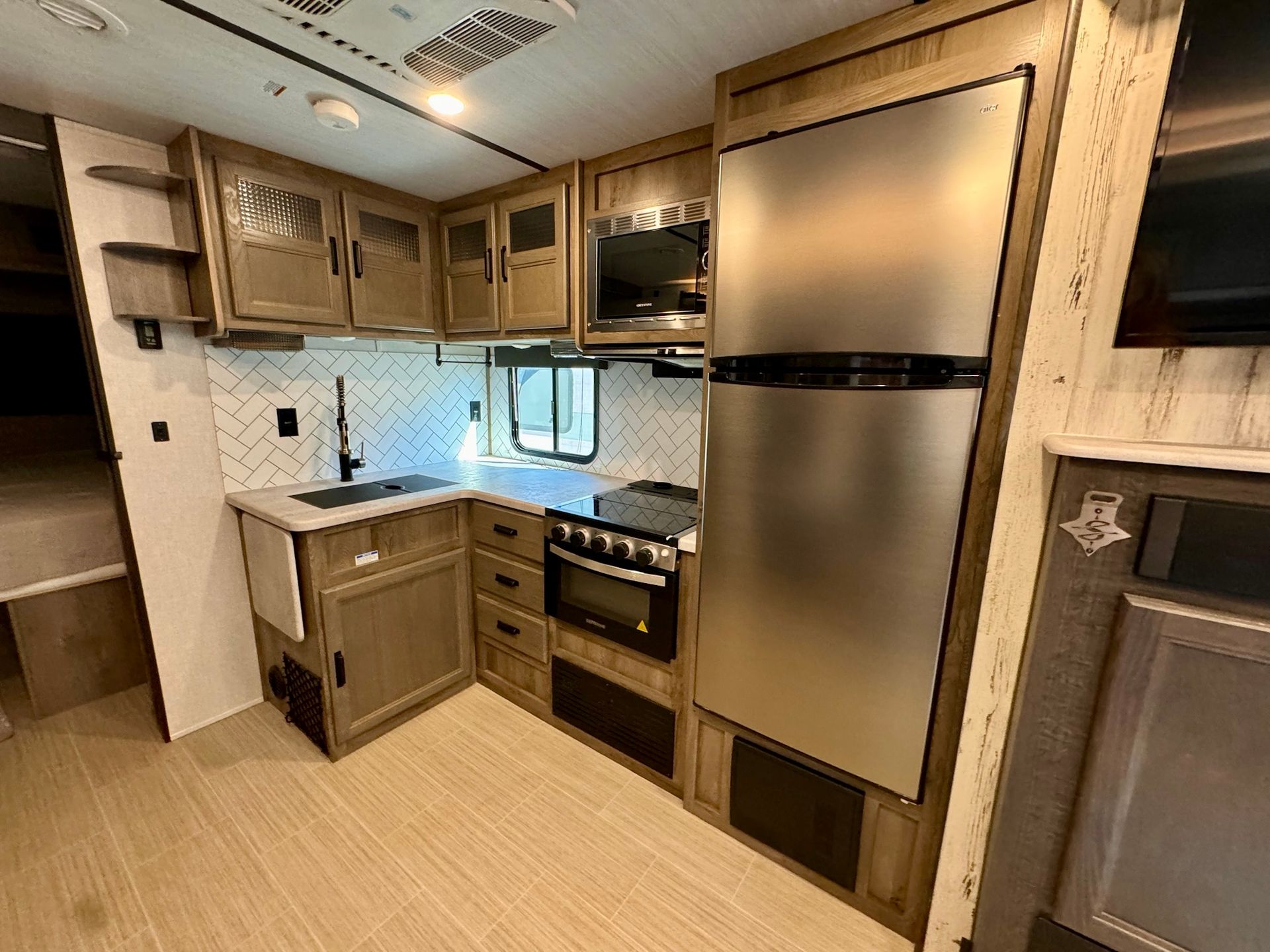 A kitchen in a rv with stainless steel appliances and wooden cabinets.