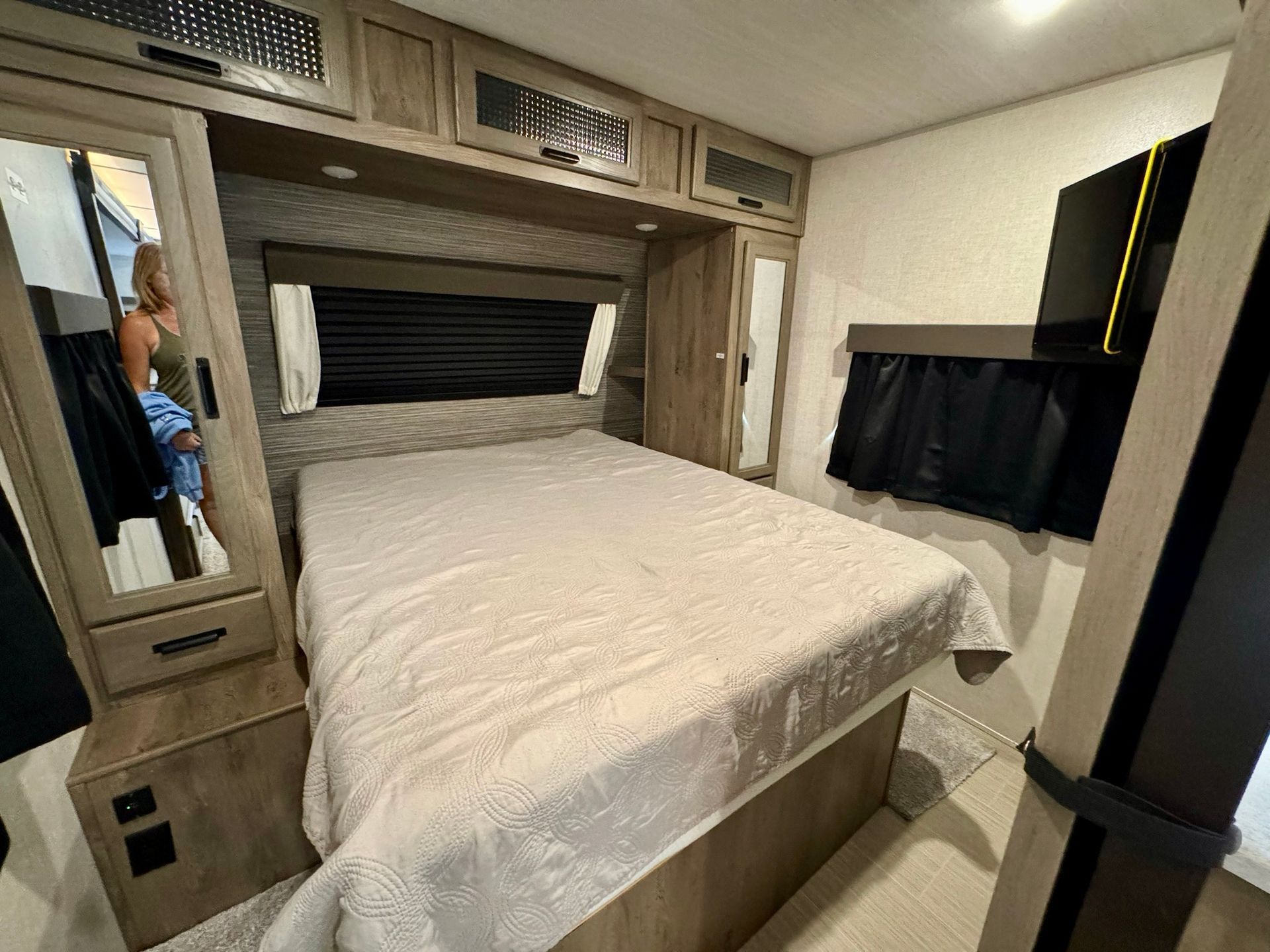 A bedroom in a rv with a bed and a mirror.