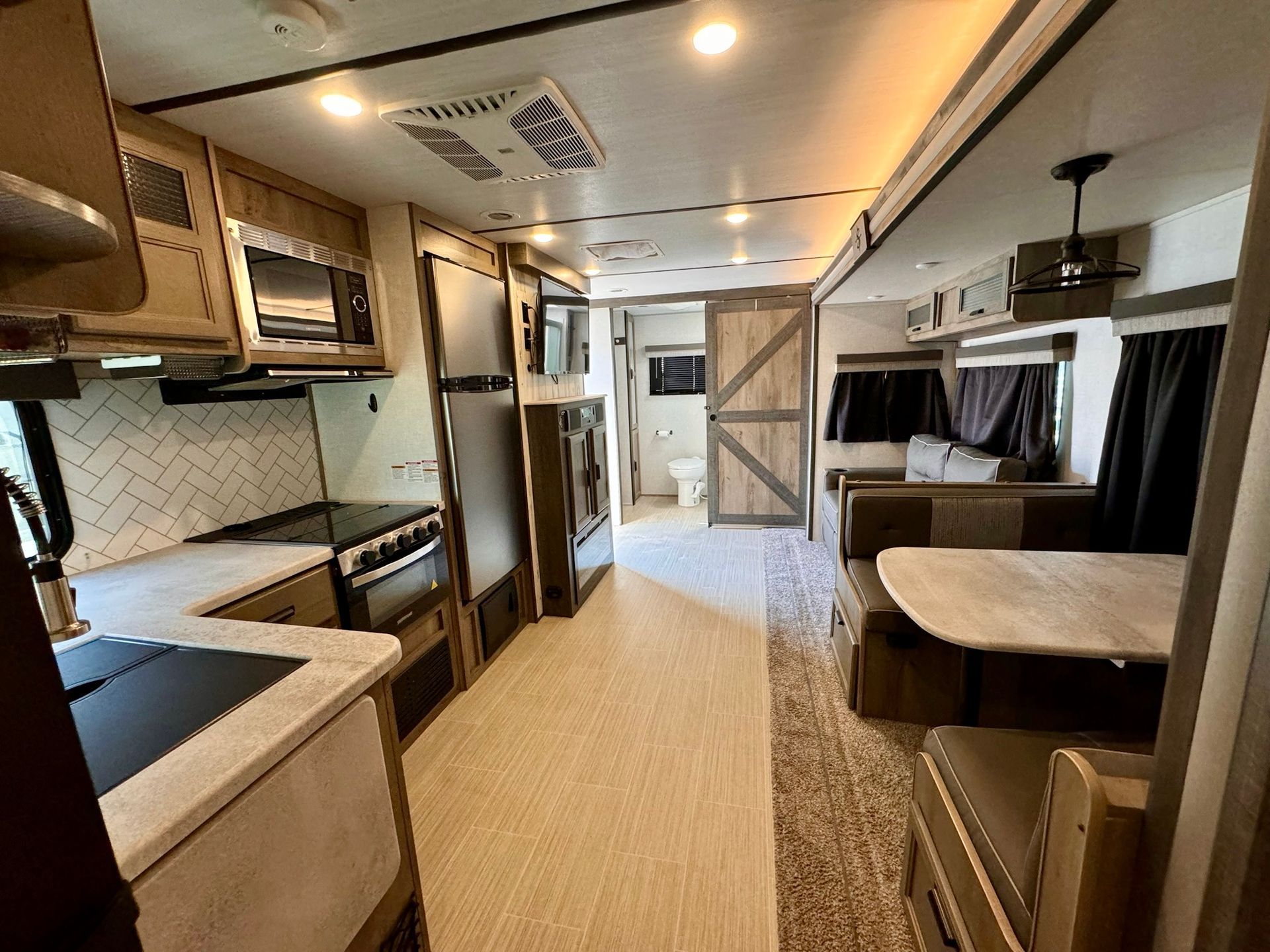 The inside of a rv with a kitchen , dining room , and living room.