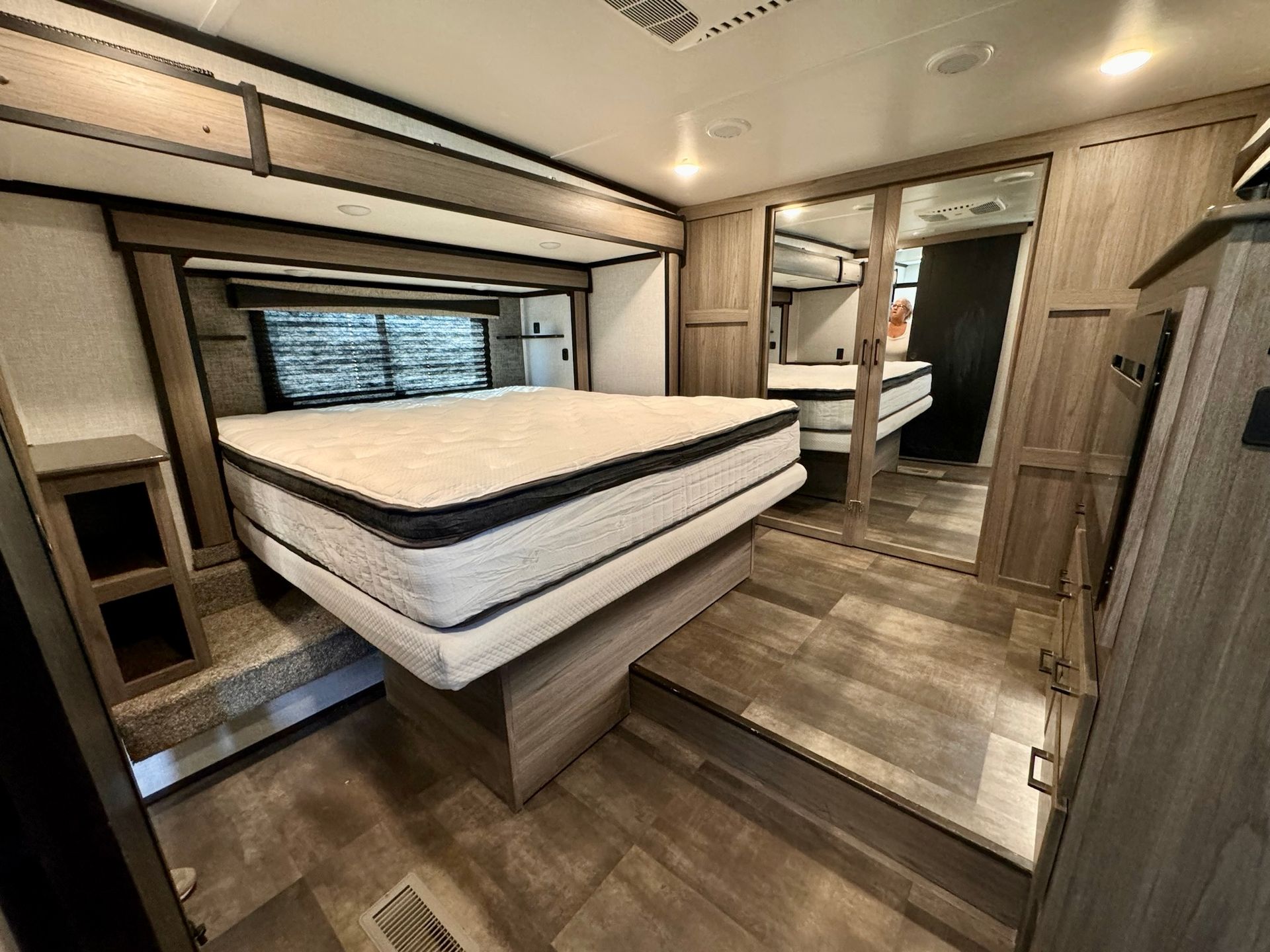 A bedroom in a rv with a bed and a mirror.