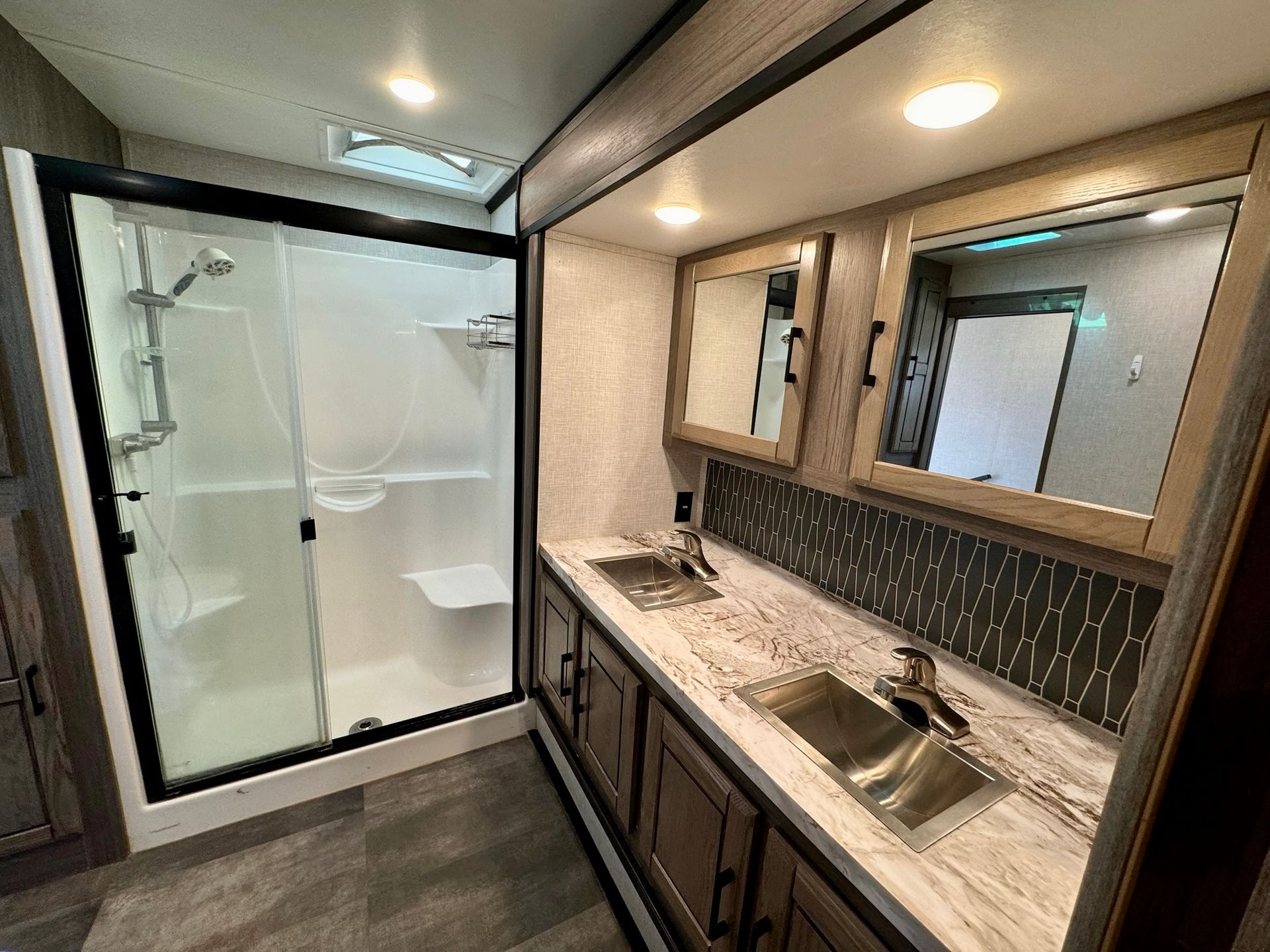 A bathroom with two sinks , a shower and a mirror.