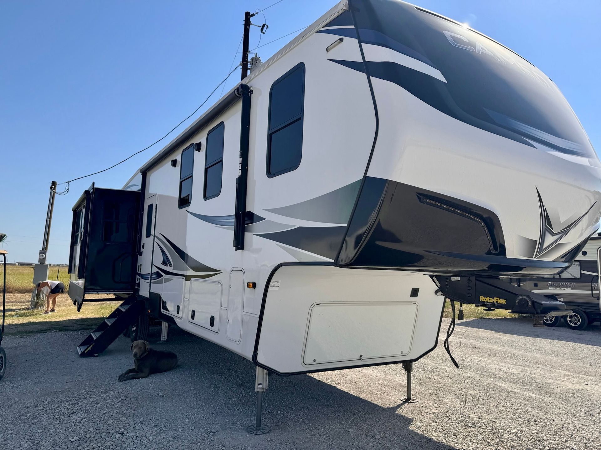 A white rv is parked in a gravel lot.