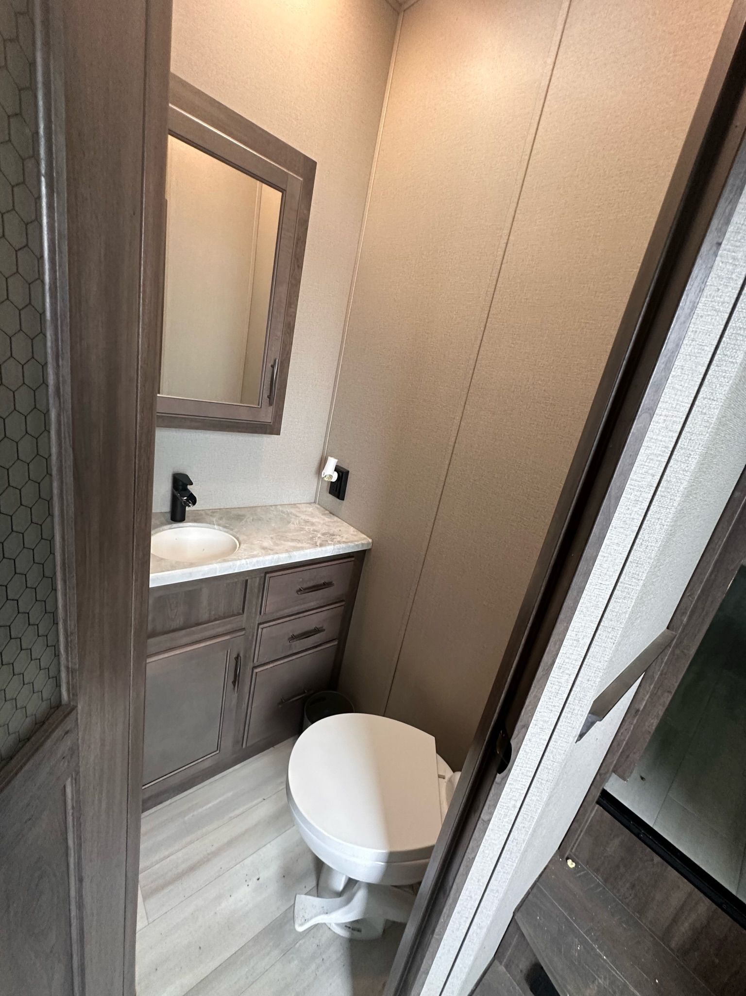 A bathroom with a toilet , sink and mirror.