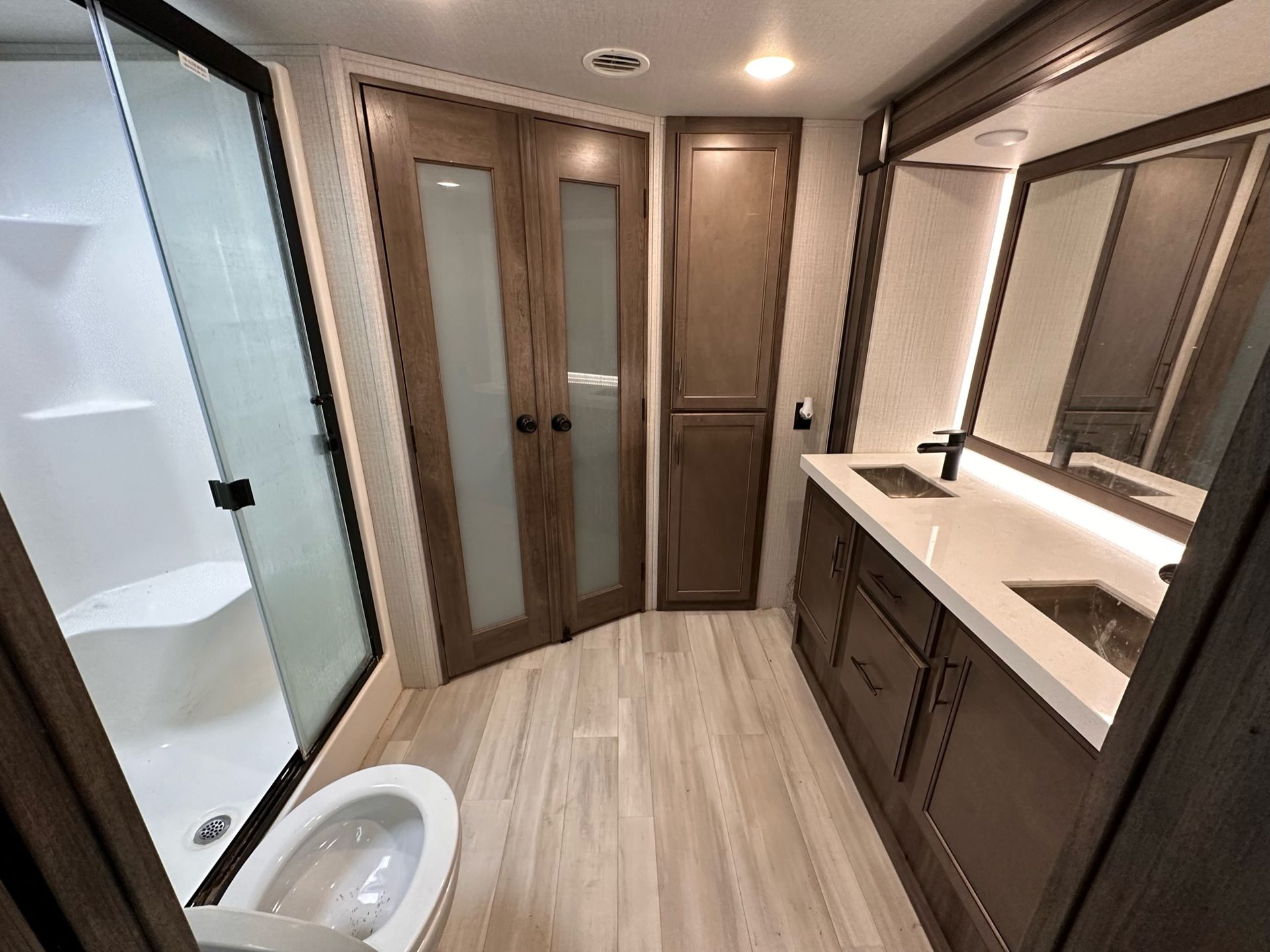 A bathroom with a toilet , sink , shower and mirror.