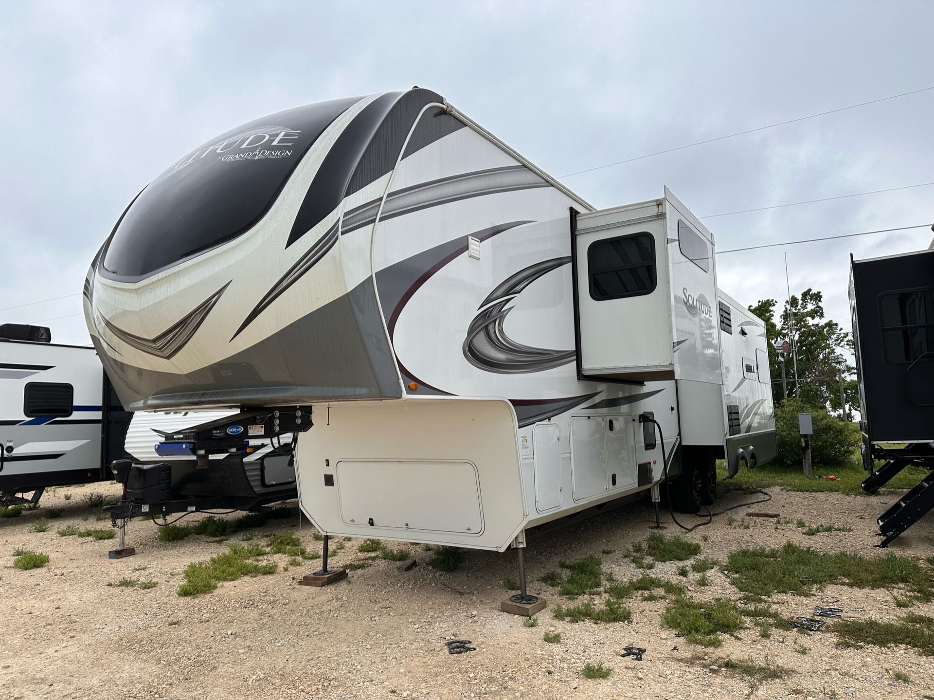 A large white rv is parked in a gravel lot.