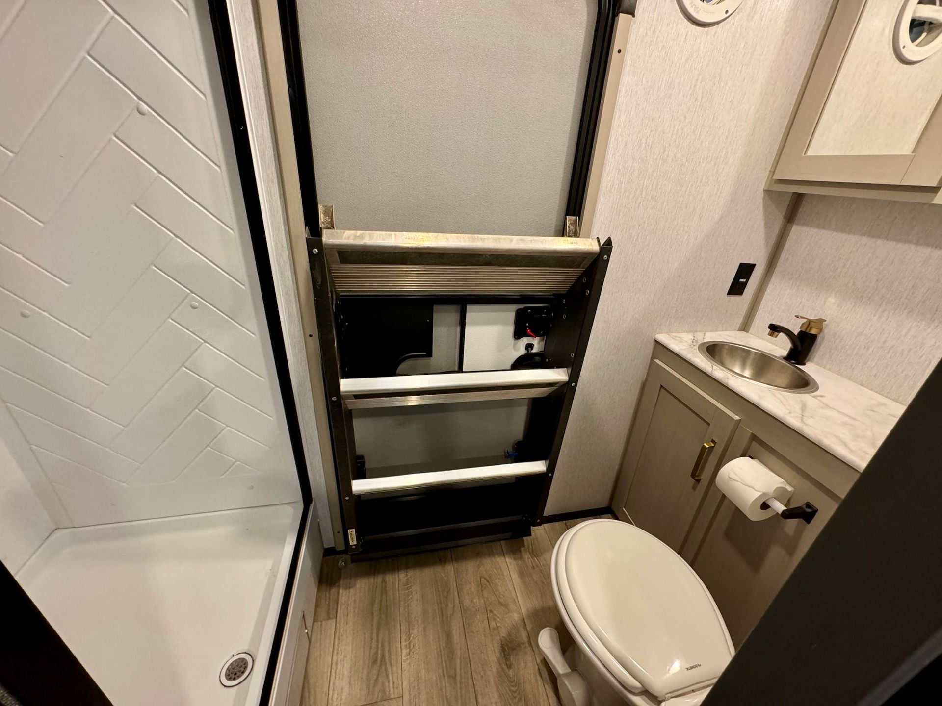 A bathroom with a toilet , sink and shower.