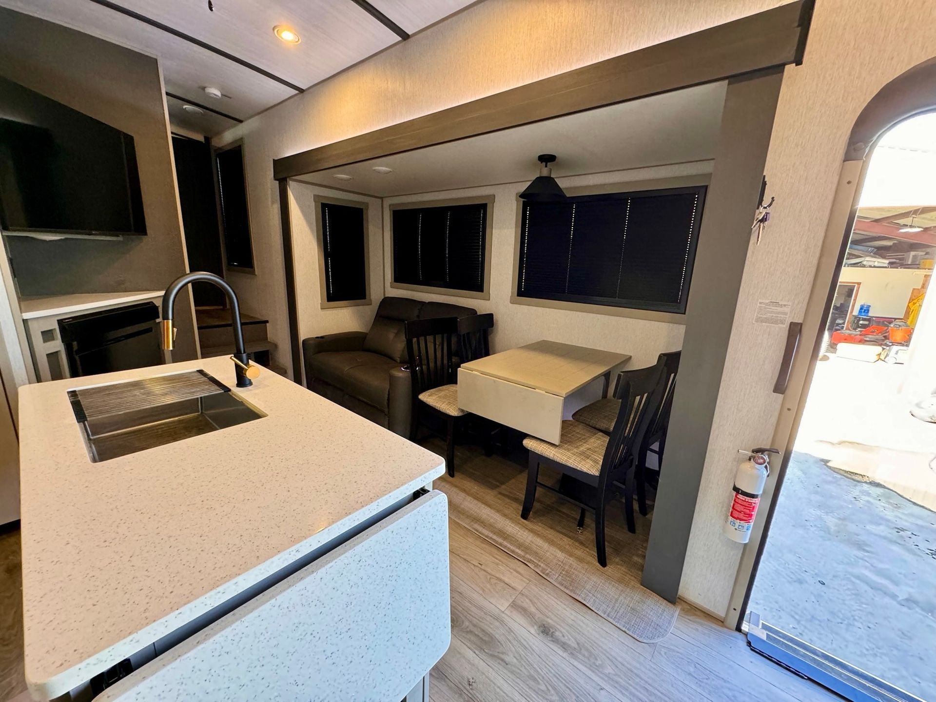 A kitchen with a sink , table , chairs and a couch.