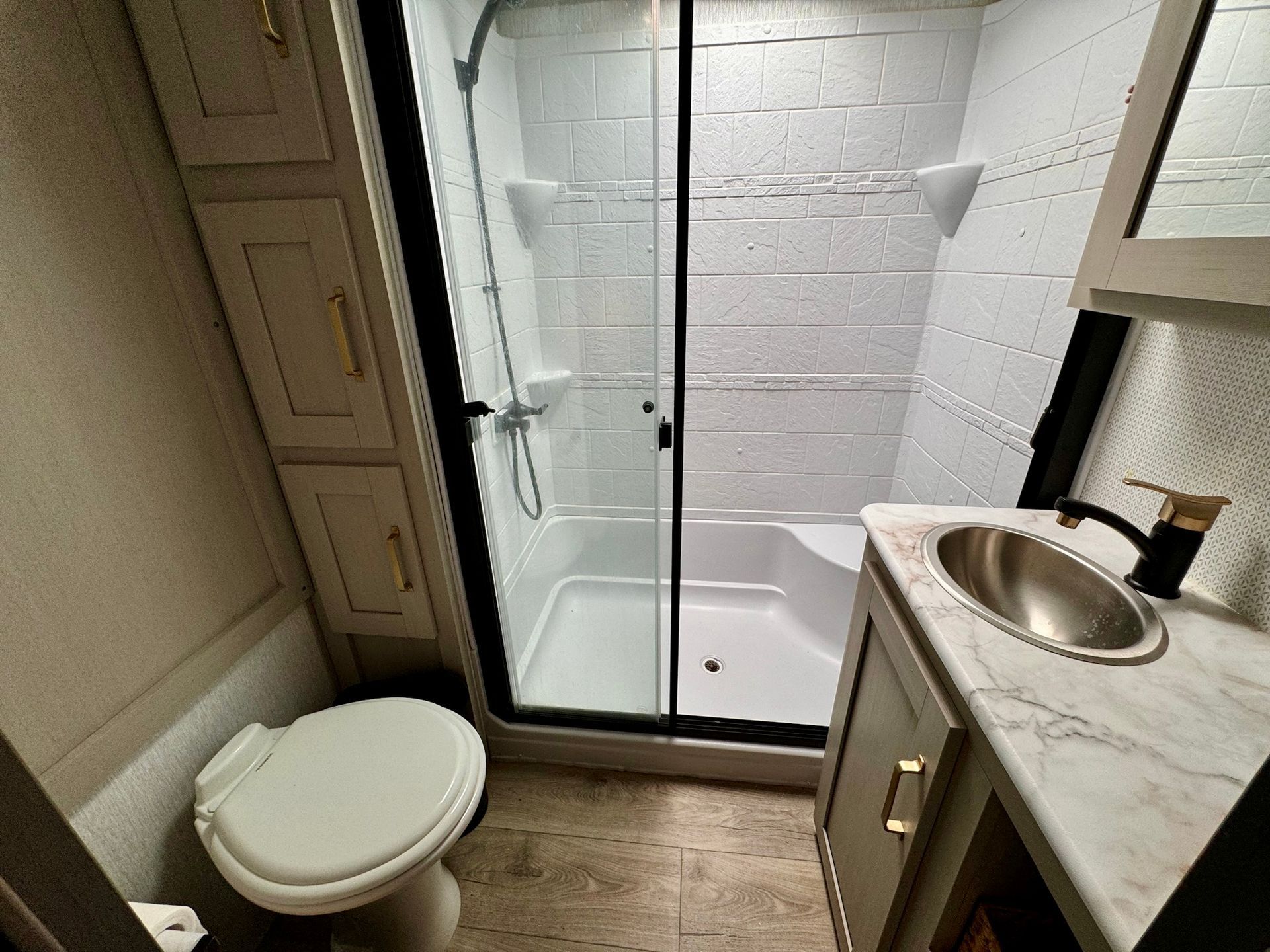 A bathroom with a toilet , sink and shower.