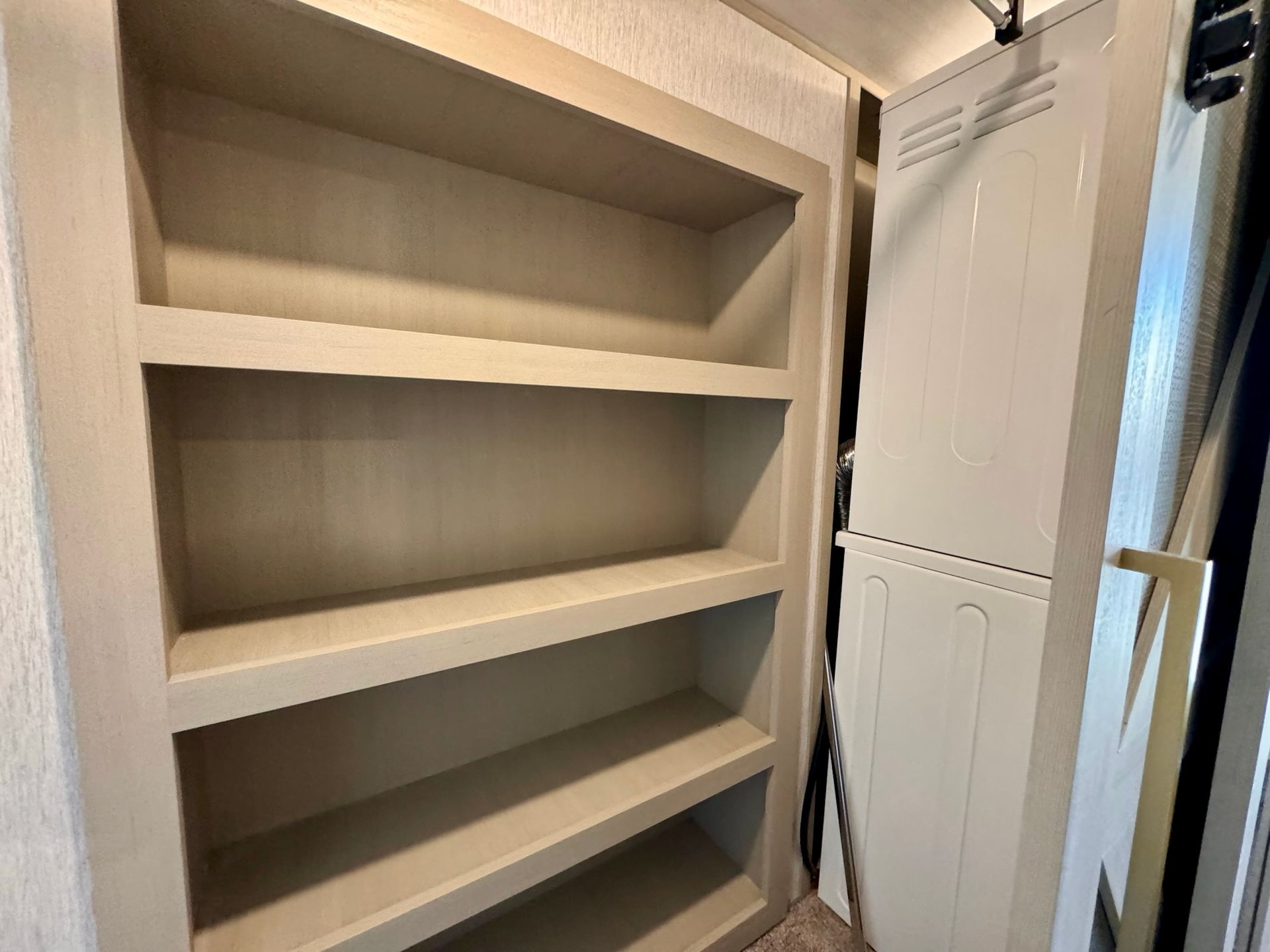 A closet with shelves and a washer and dryer in it.