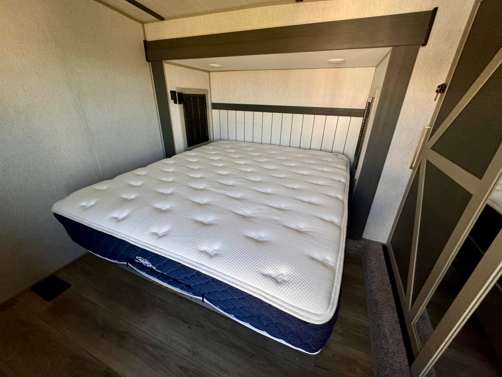 A bed with a mattress and a headboard in a room.