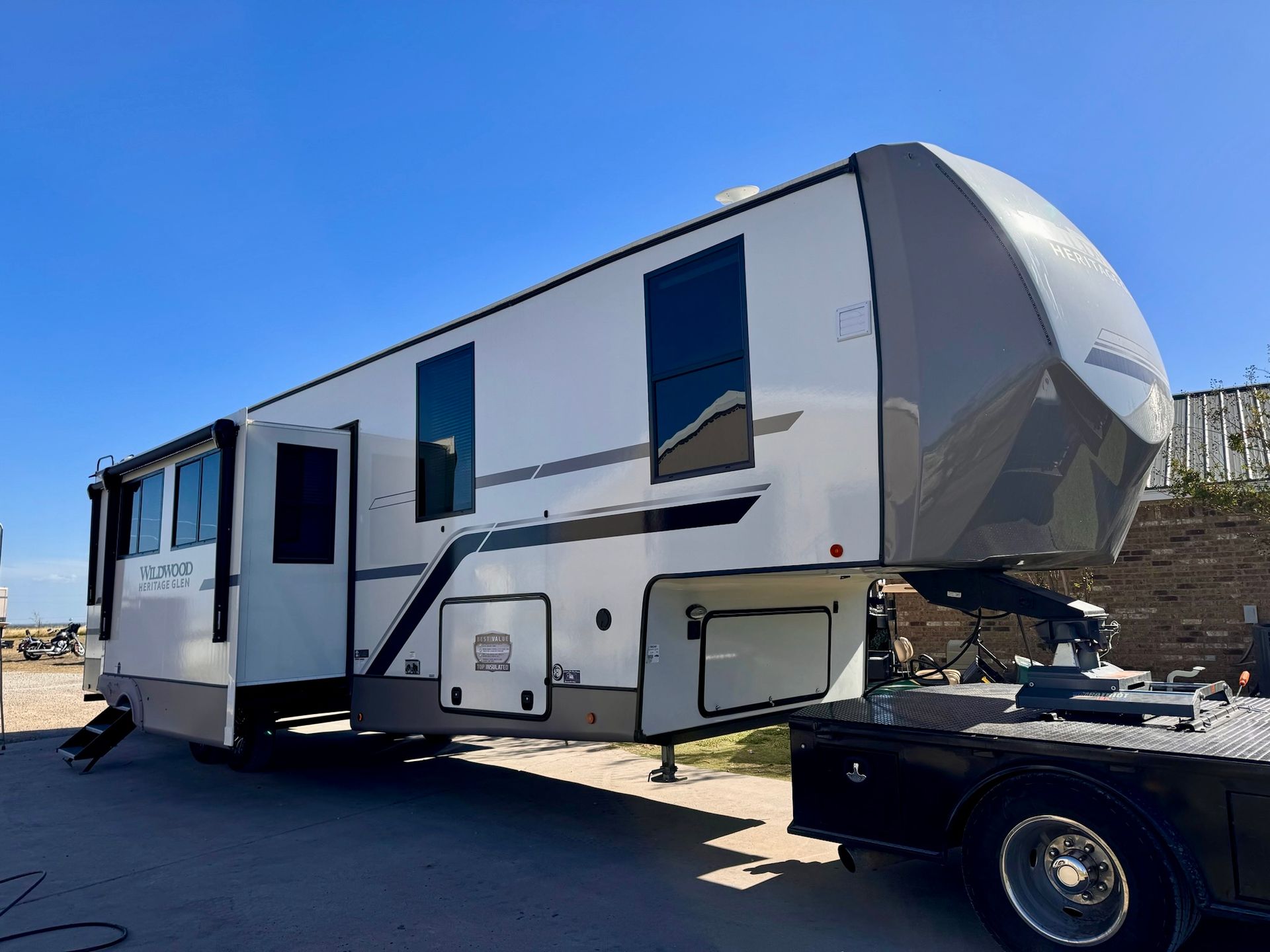 A large white rv is being towed by a truck.