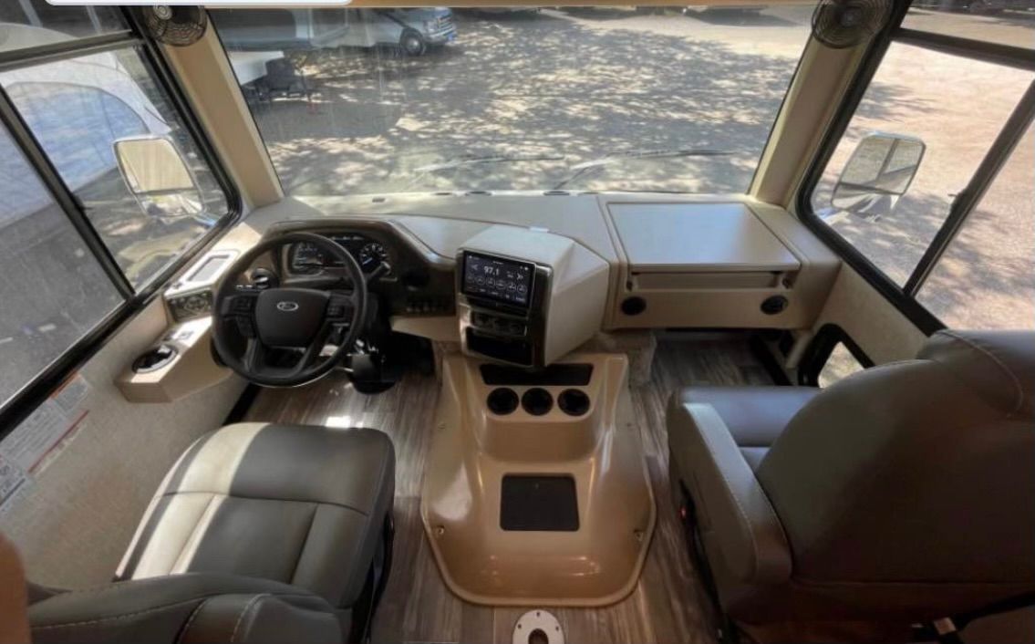 The interior of a rv with a steering wheel and seats.