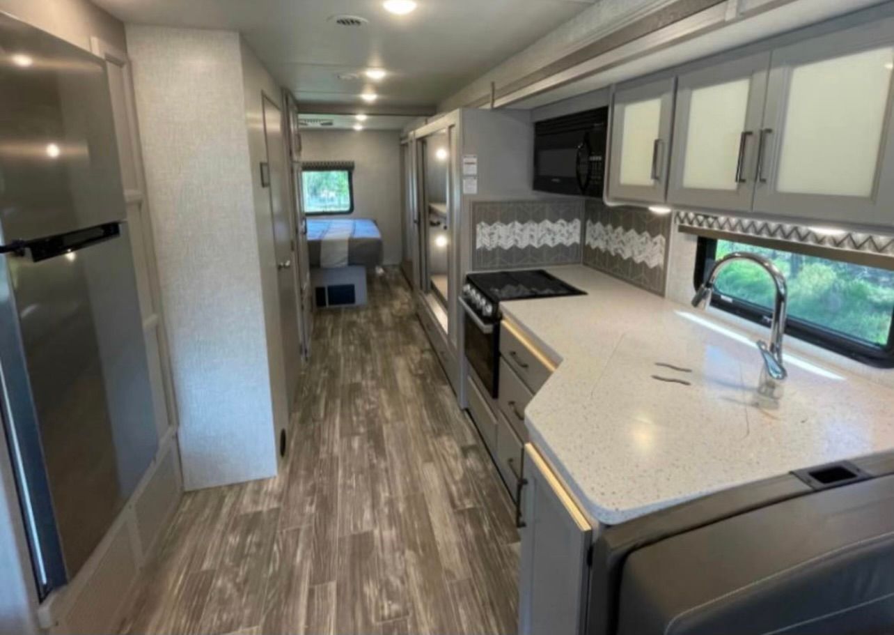 The inside of a rv with a kitchen and a refrigerator.