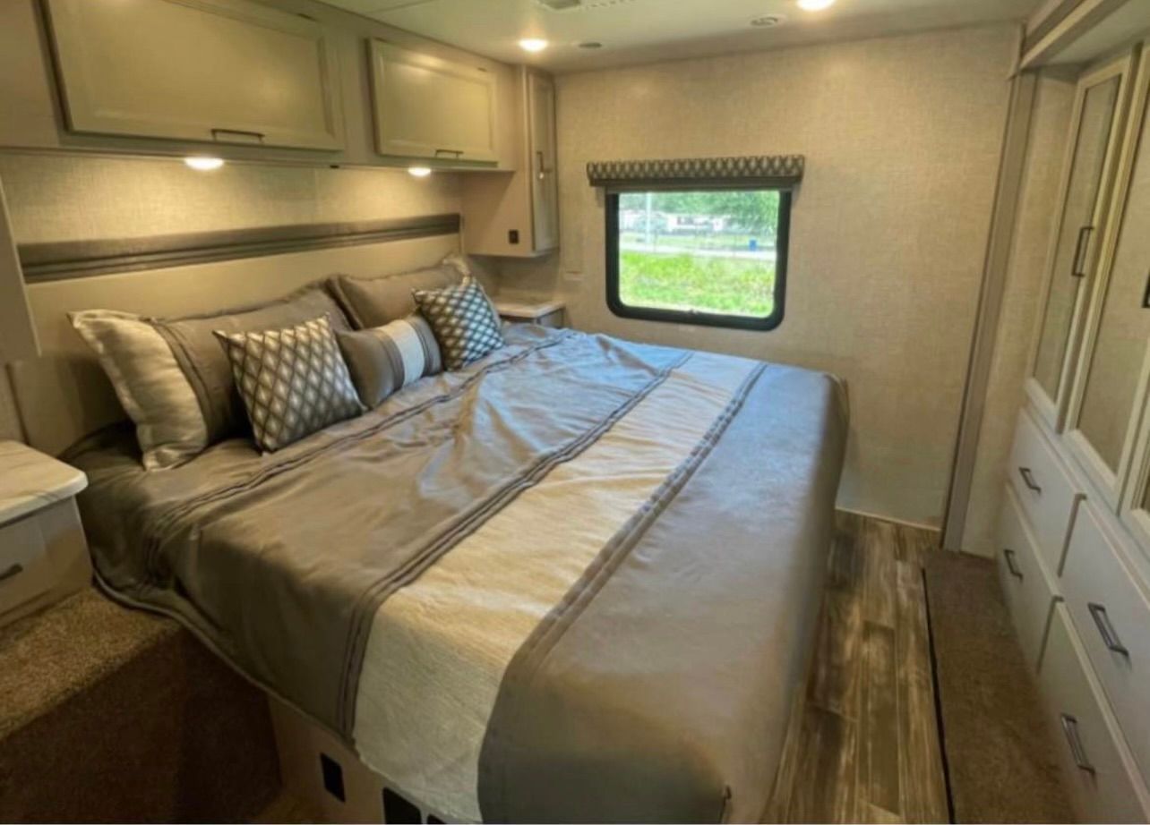 A bedroom in a rv with a large bed and a window.