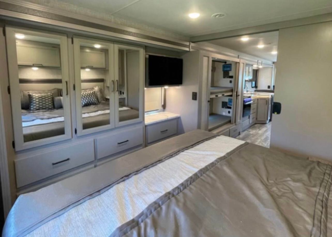 A bedroom in a rv with a bed and a television.
