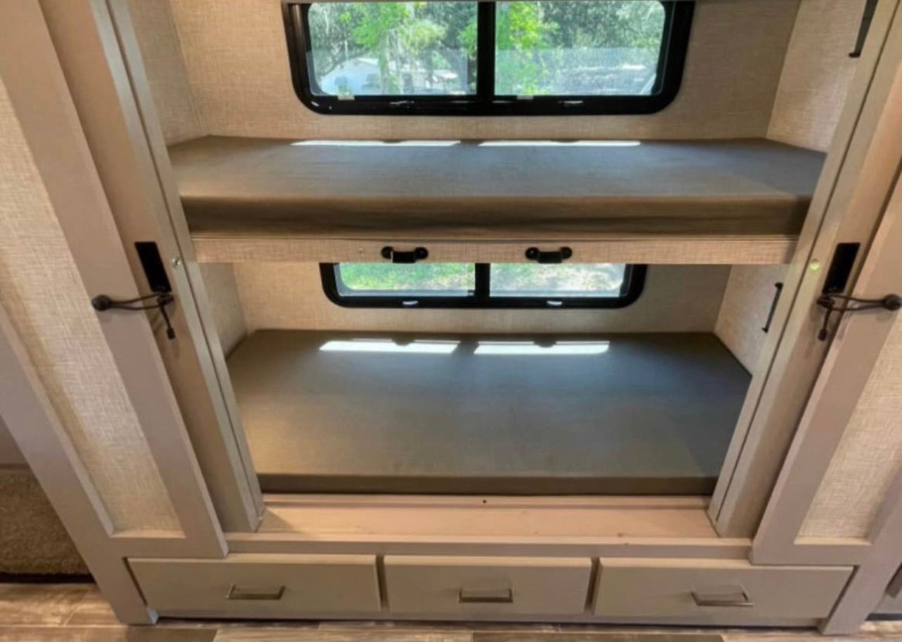 The inside of a rv with bunk beds and drawers.