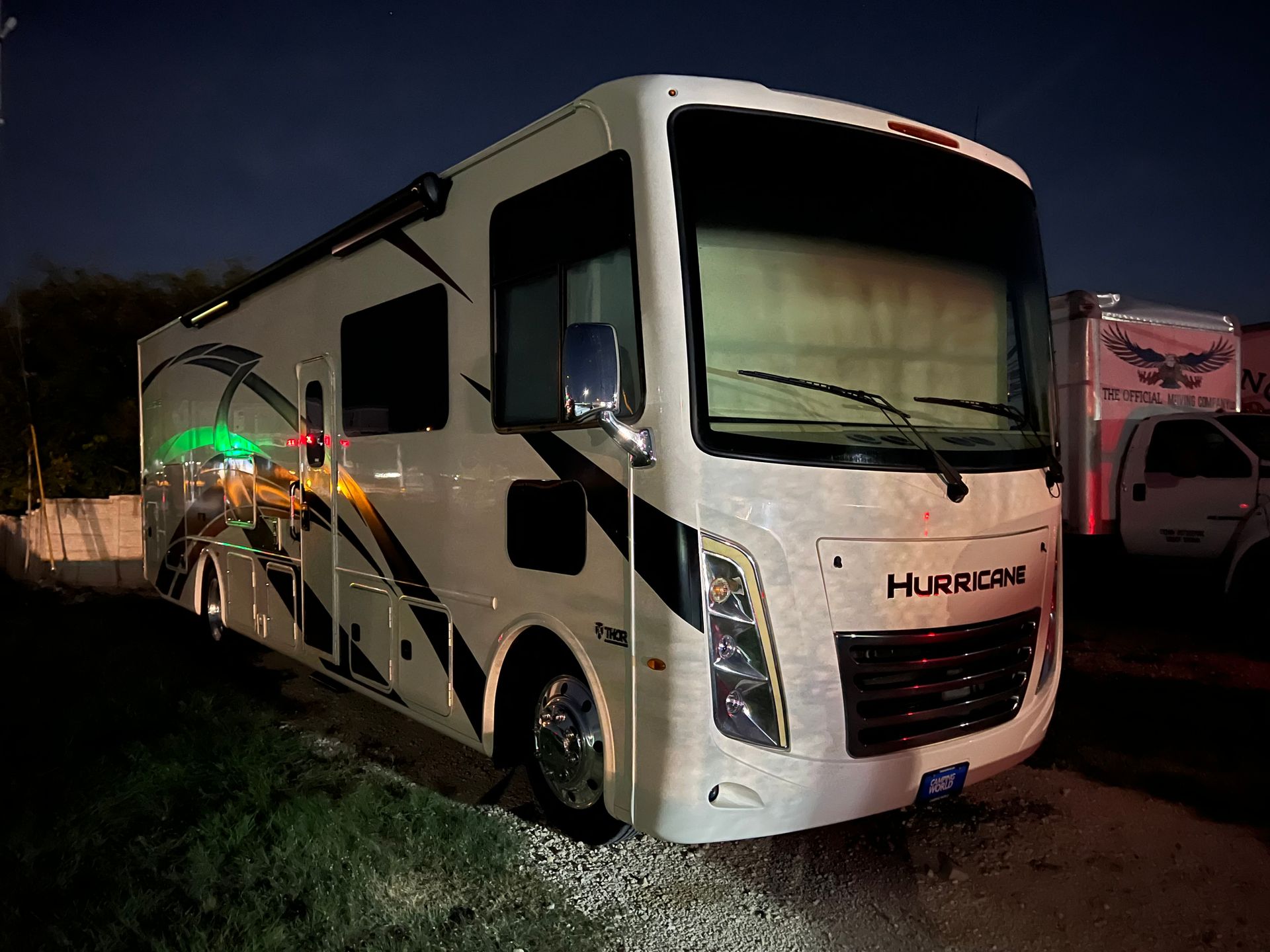 A white rv is parked on the side of the road at night.
