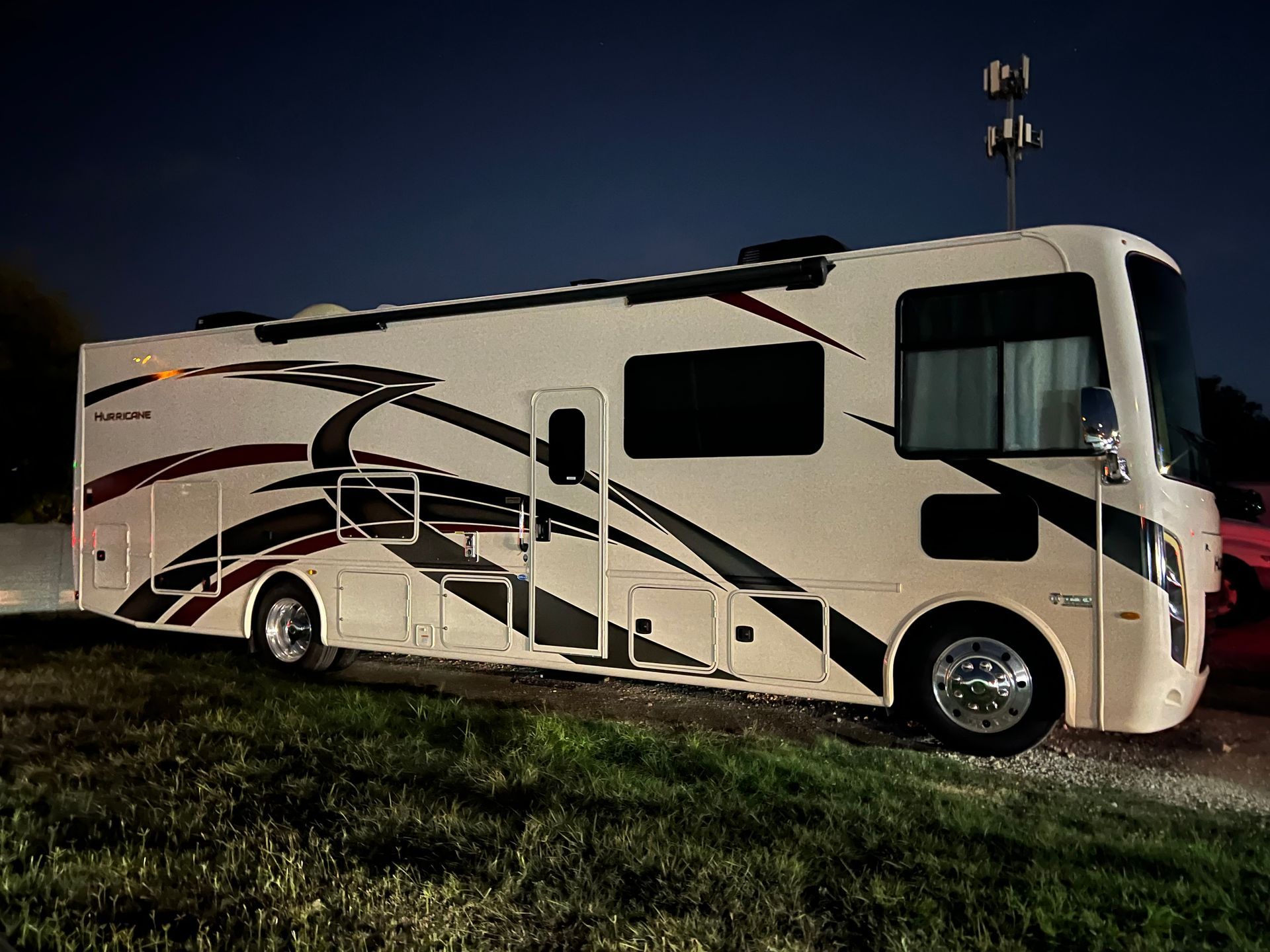 A large white rv is parked in a grassy field at night.