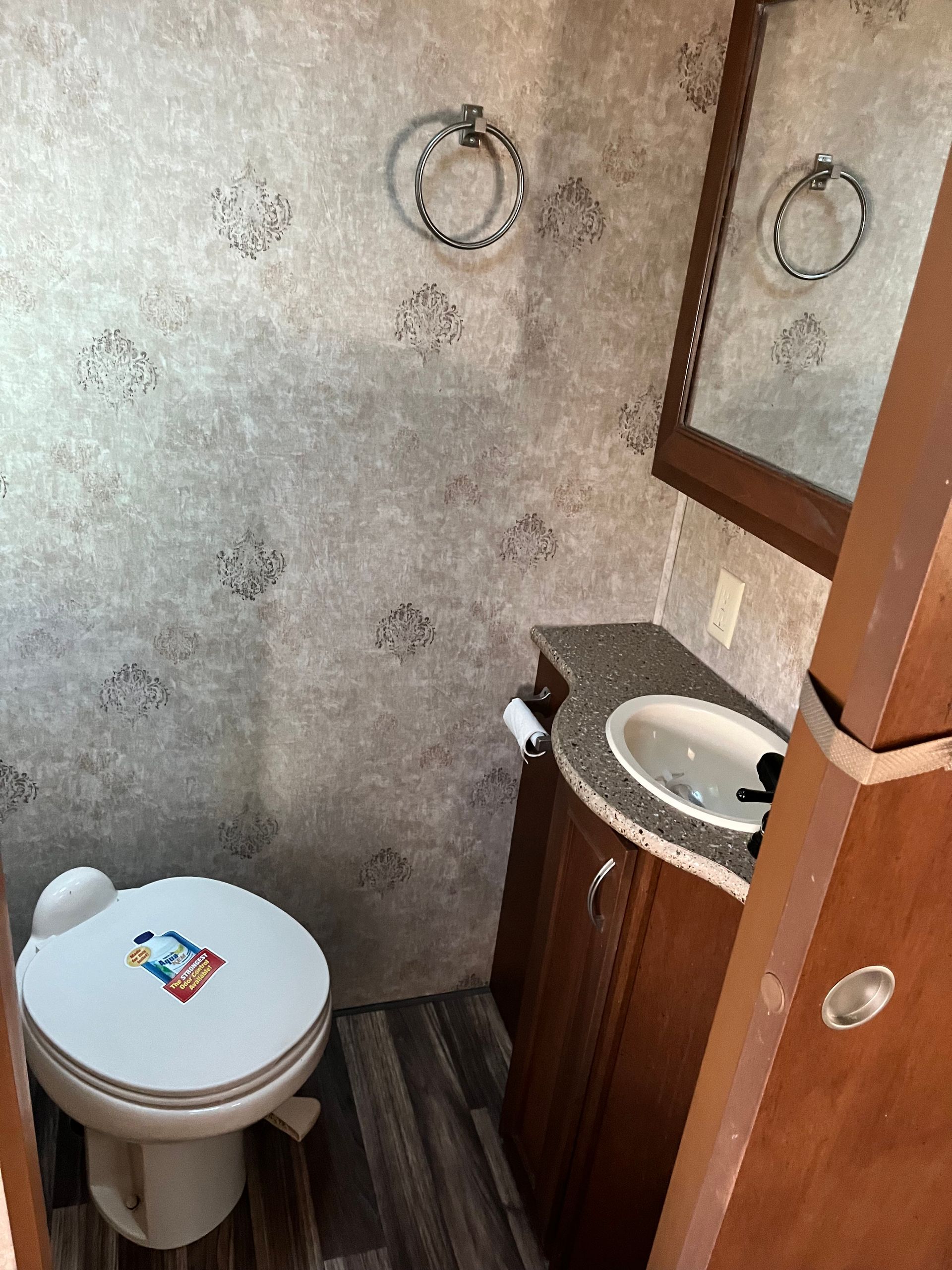A bathroom with a toilet , sink and mirror.