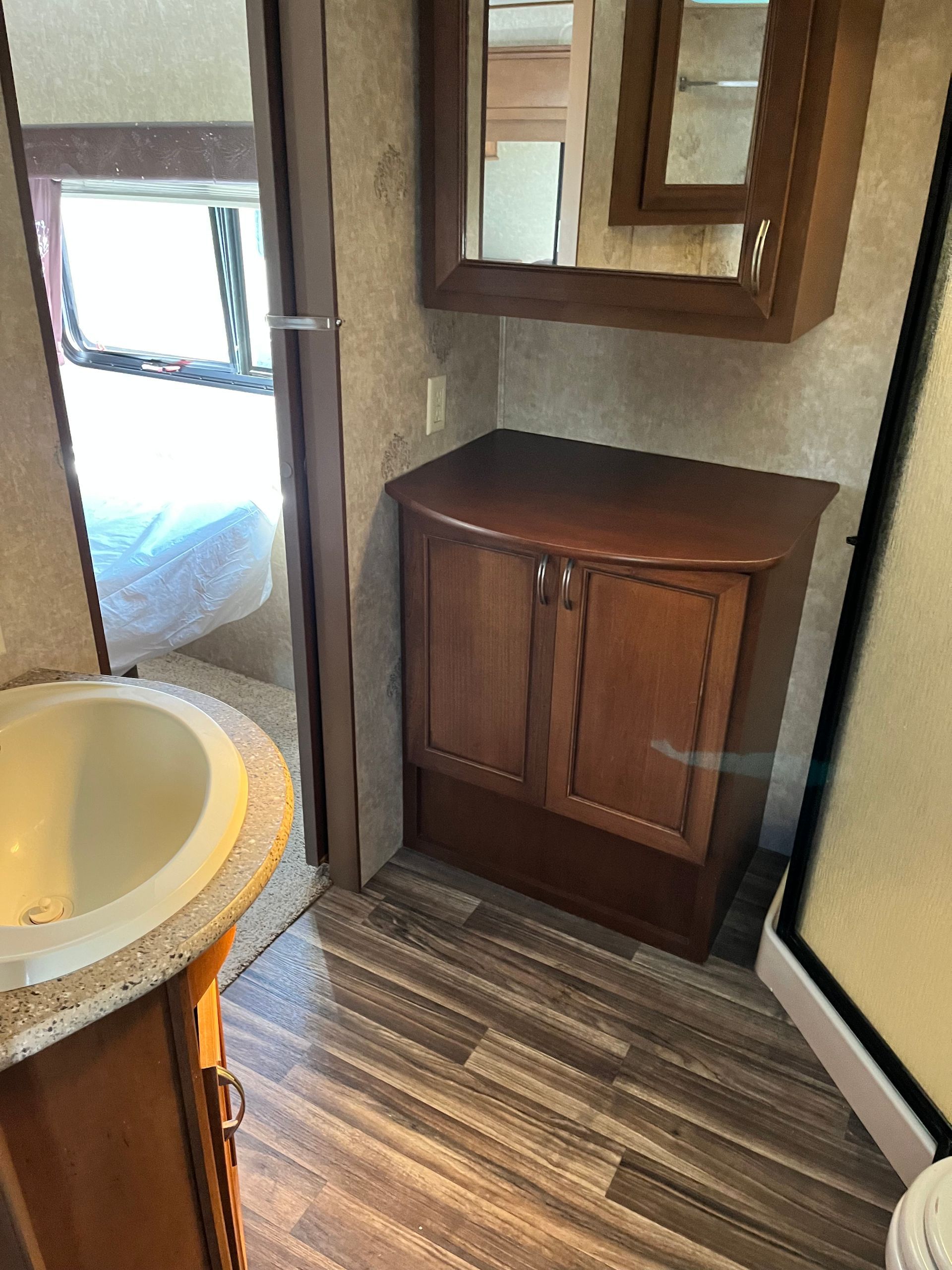 A bathroom with a sink , cabinet , mirror and toilet.