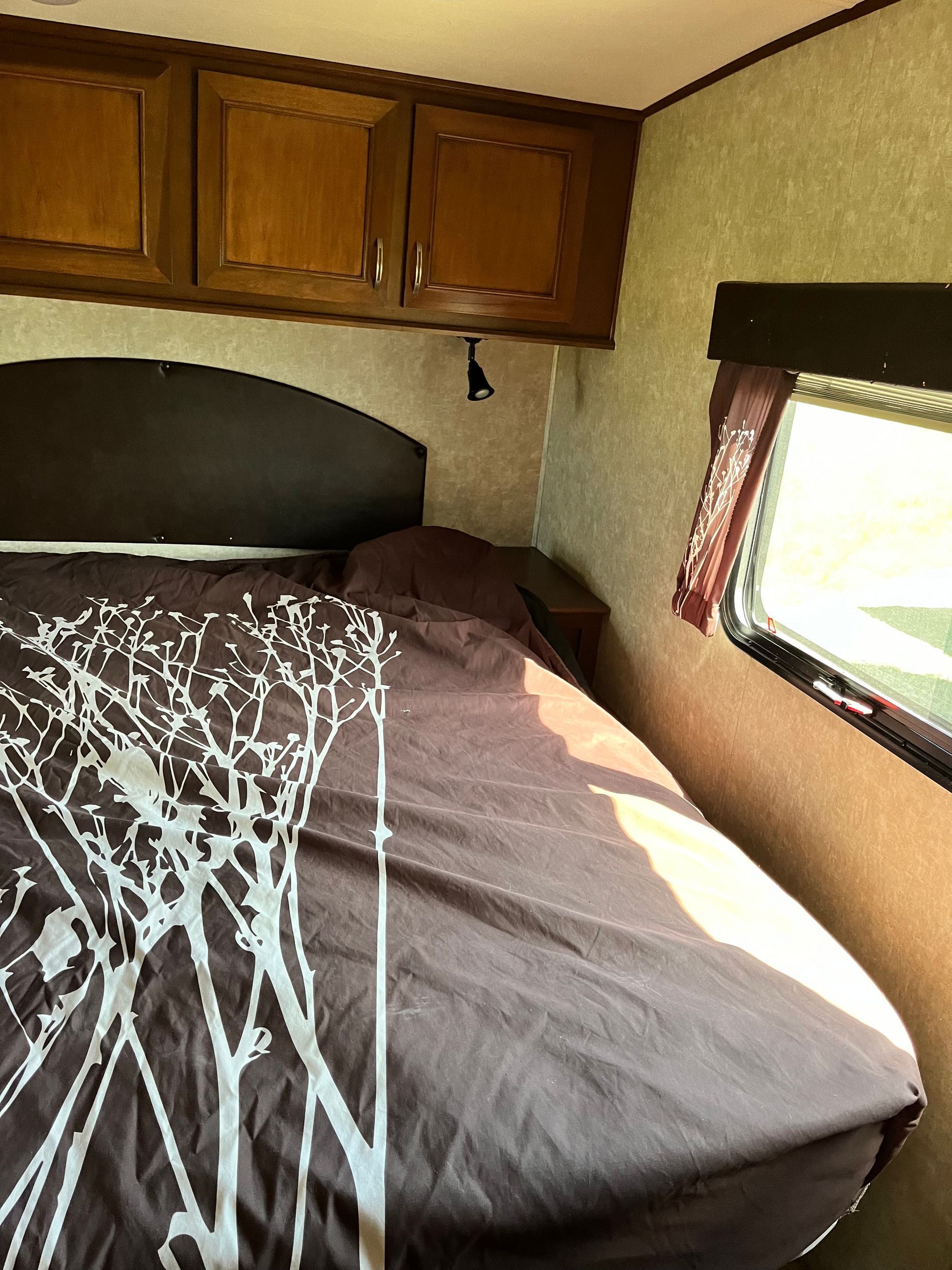 A bedroom in a camper with a bed and a window