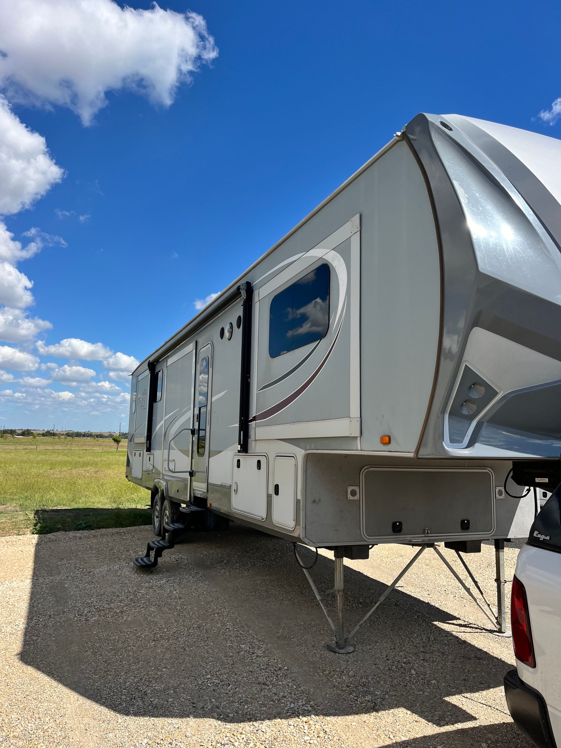 A trailer is parked in a gravel lot next to a truck.