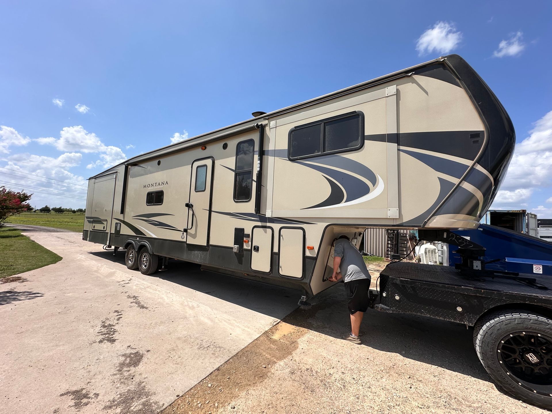 A man is towing a large rv down a dirt road.