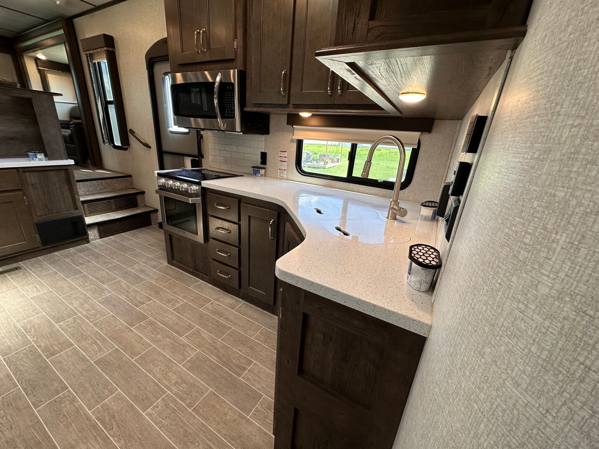 A kitchen in a trailer with stainless steel appliances and wooden cabinets.