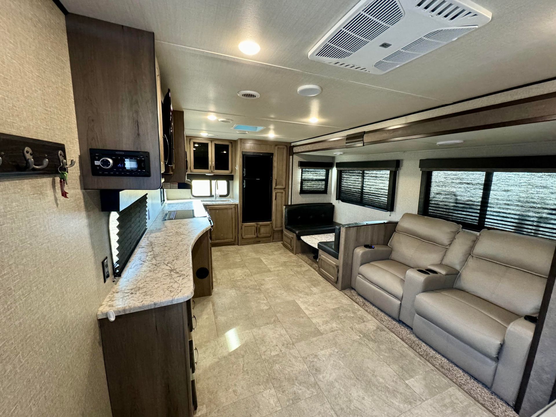 The inside of a rv with a couch , chairs , and a kitchen.