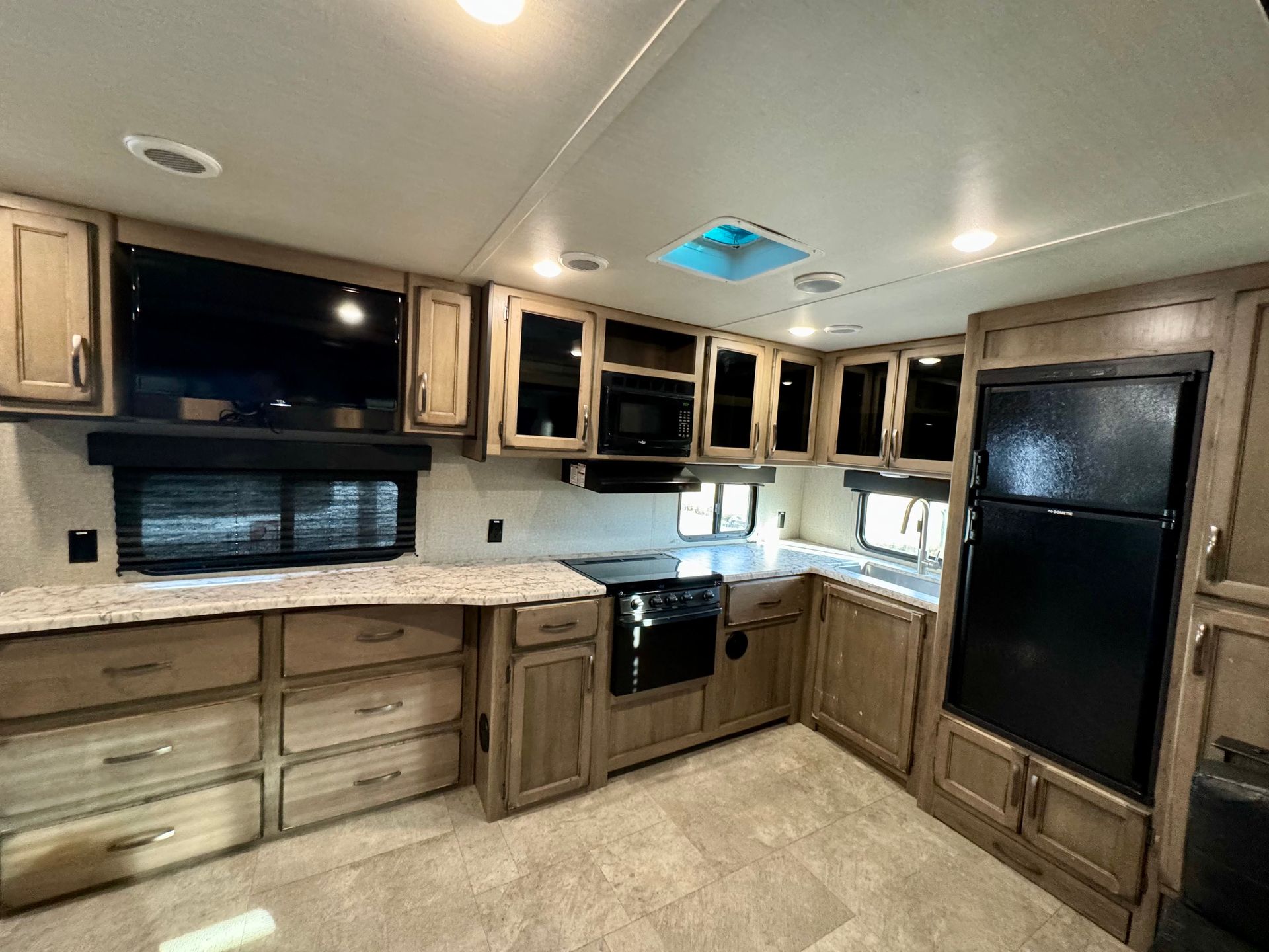 A kitchen in a rv with wooden cabinets and granite counter tops.