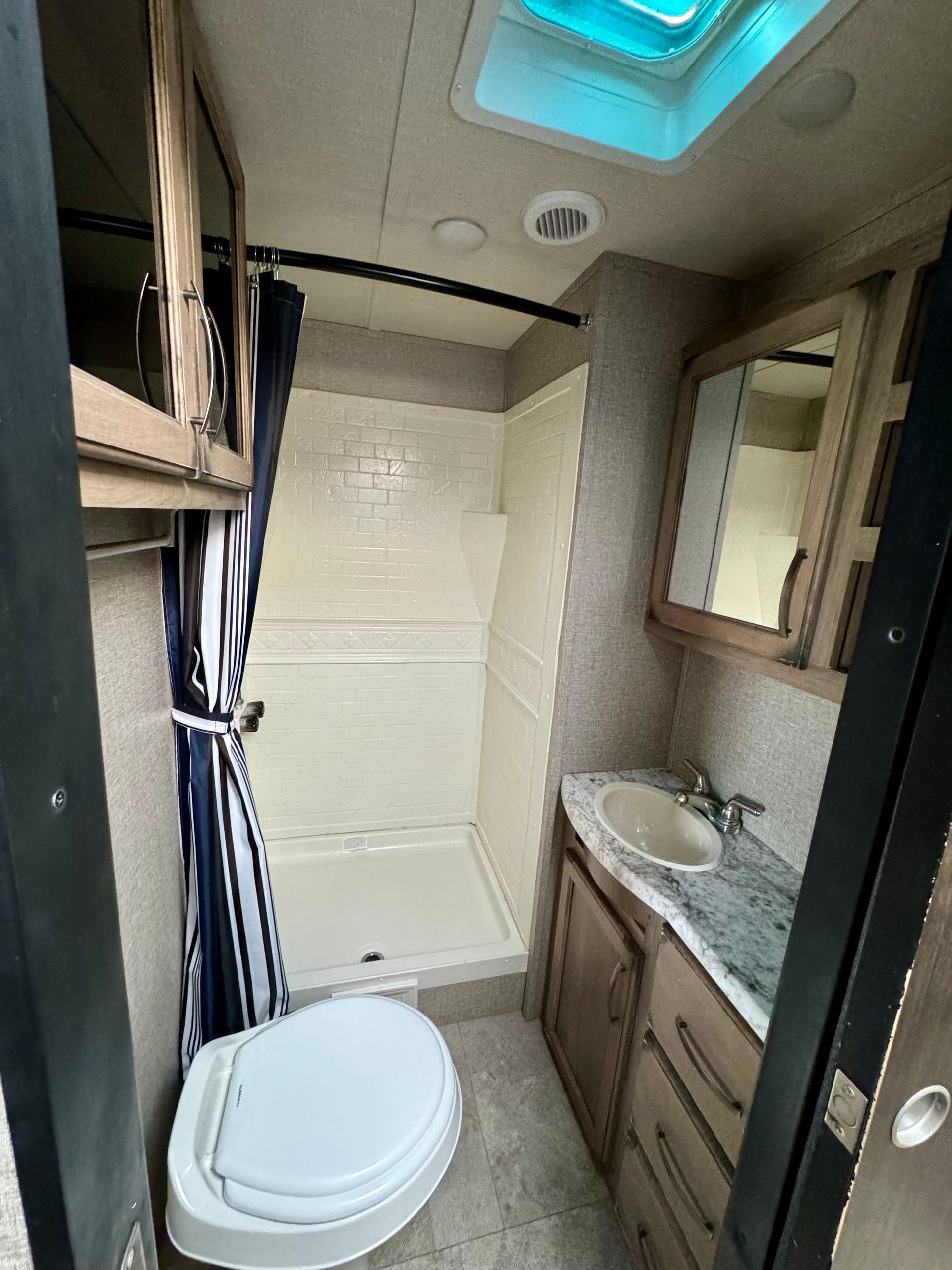 A bathroom with a toilet , sink and shower.