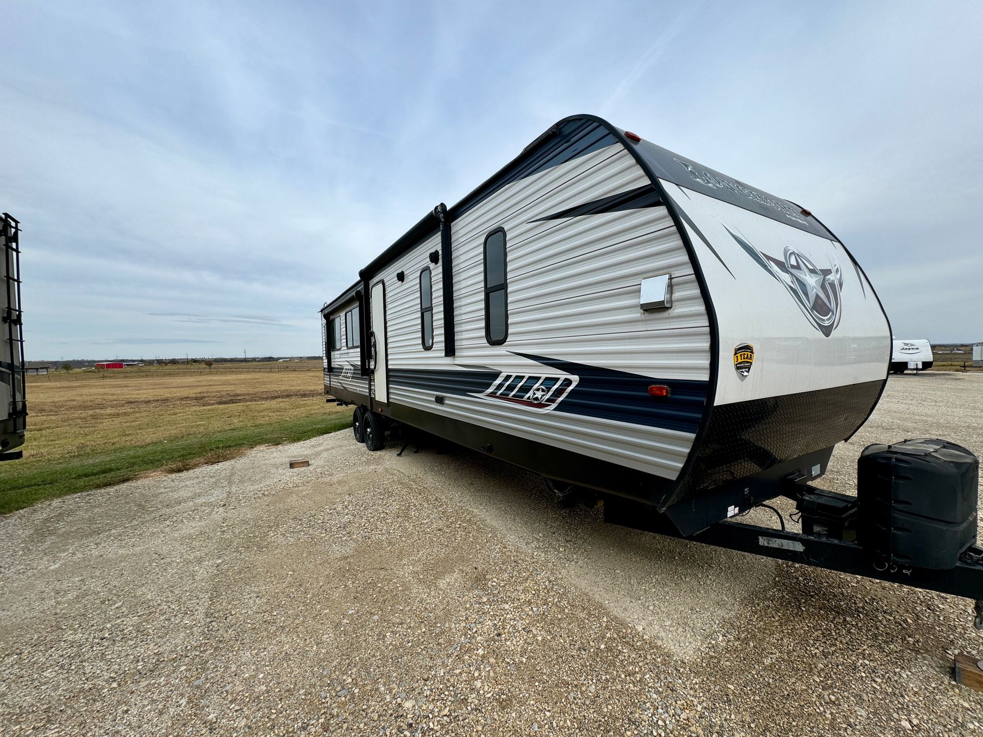 A trailer is parked on a gravel road in a field.