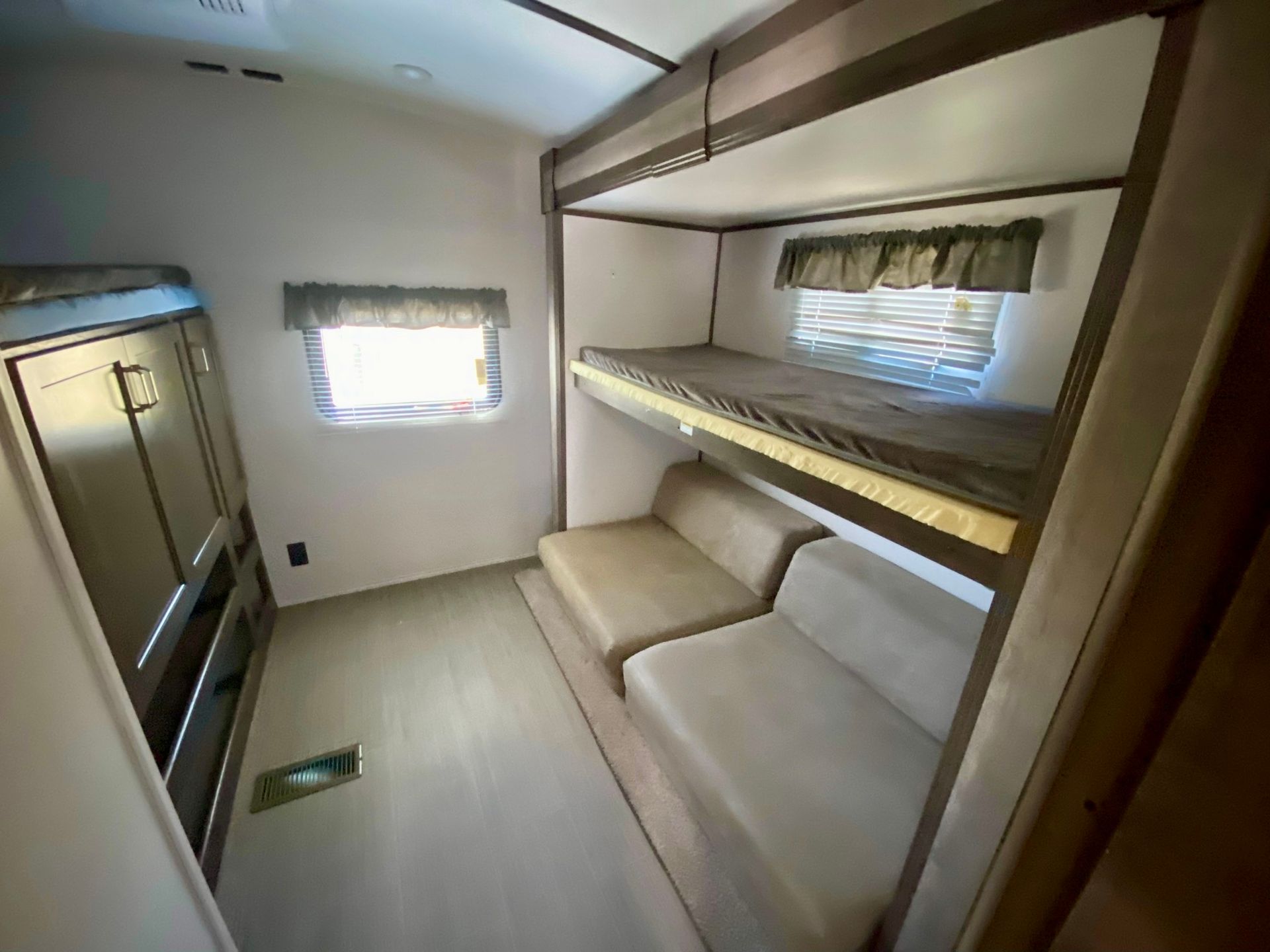 A room with bunk beds , a couch , and a window.