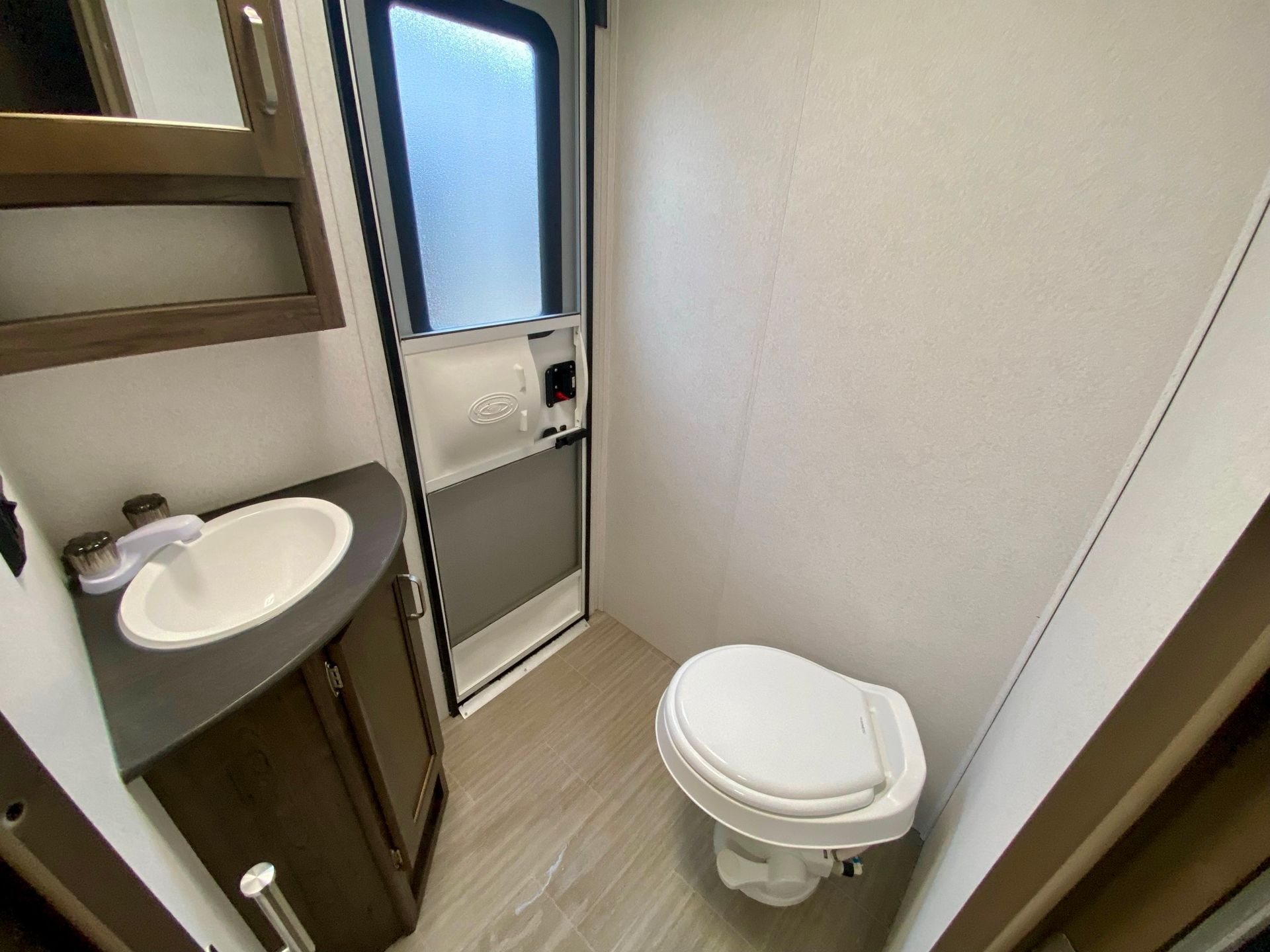 A bathroom with a toilet , sink and mirror.