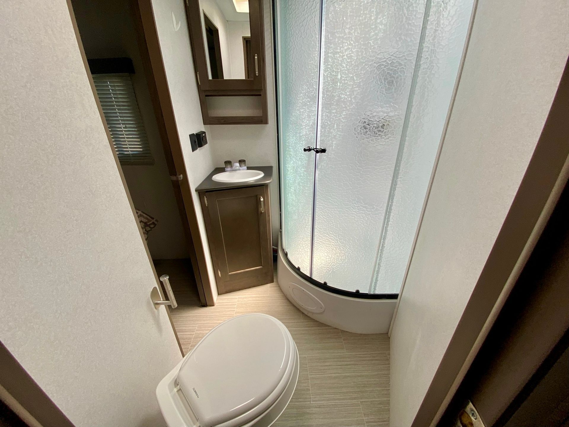 A bathroom with a toilet , sink and shower.