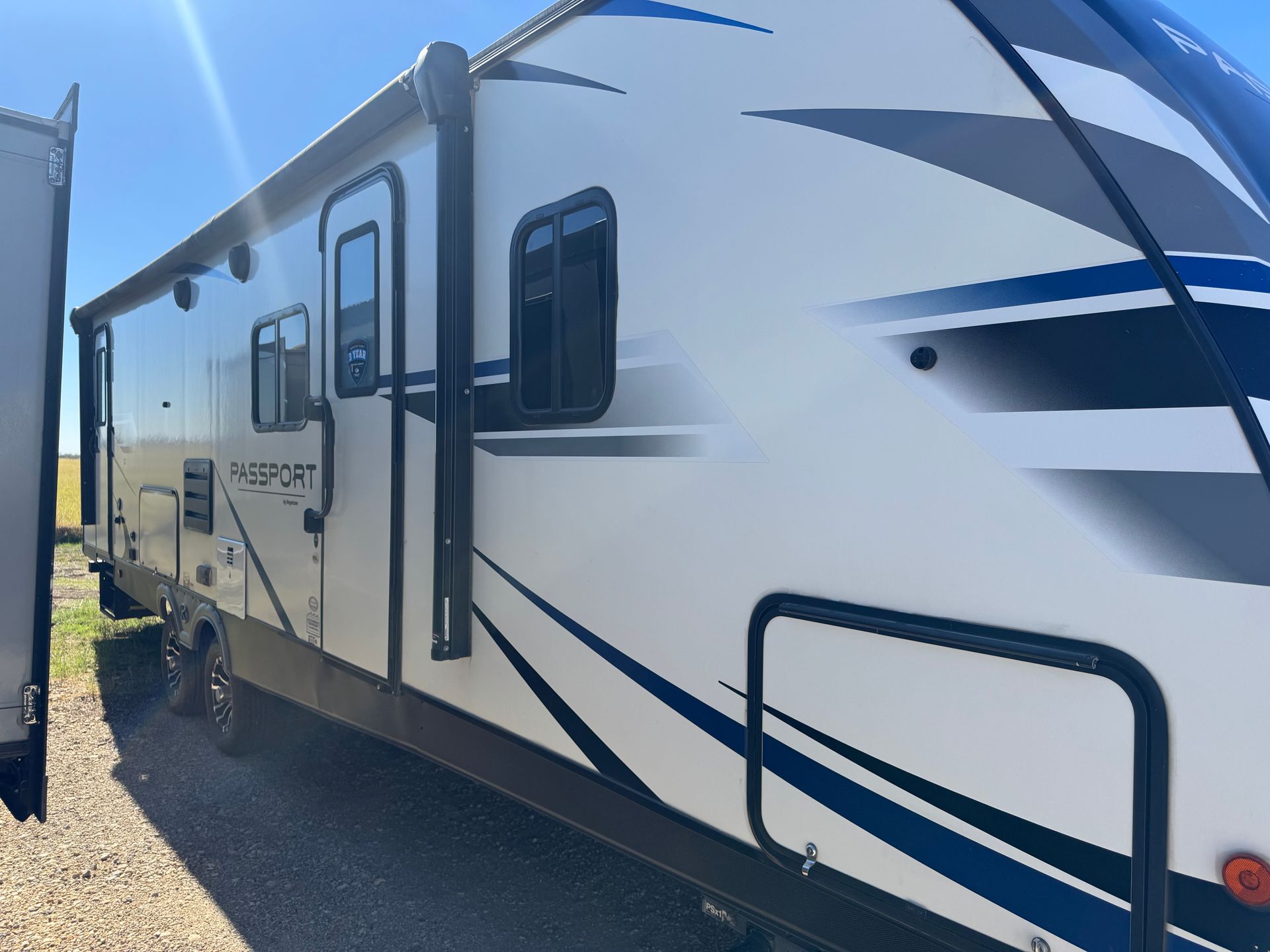A white and blue rv is parked on the side of the road.