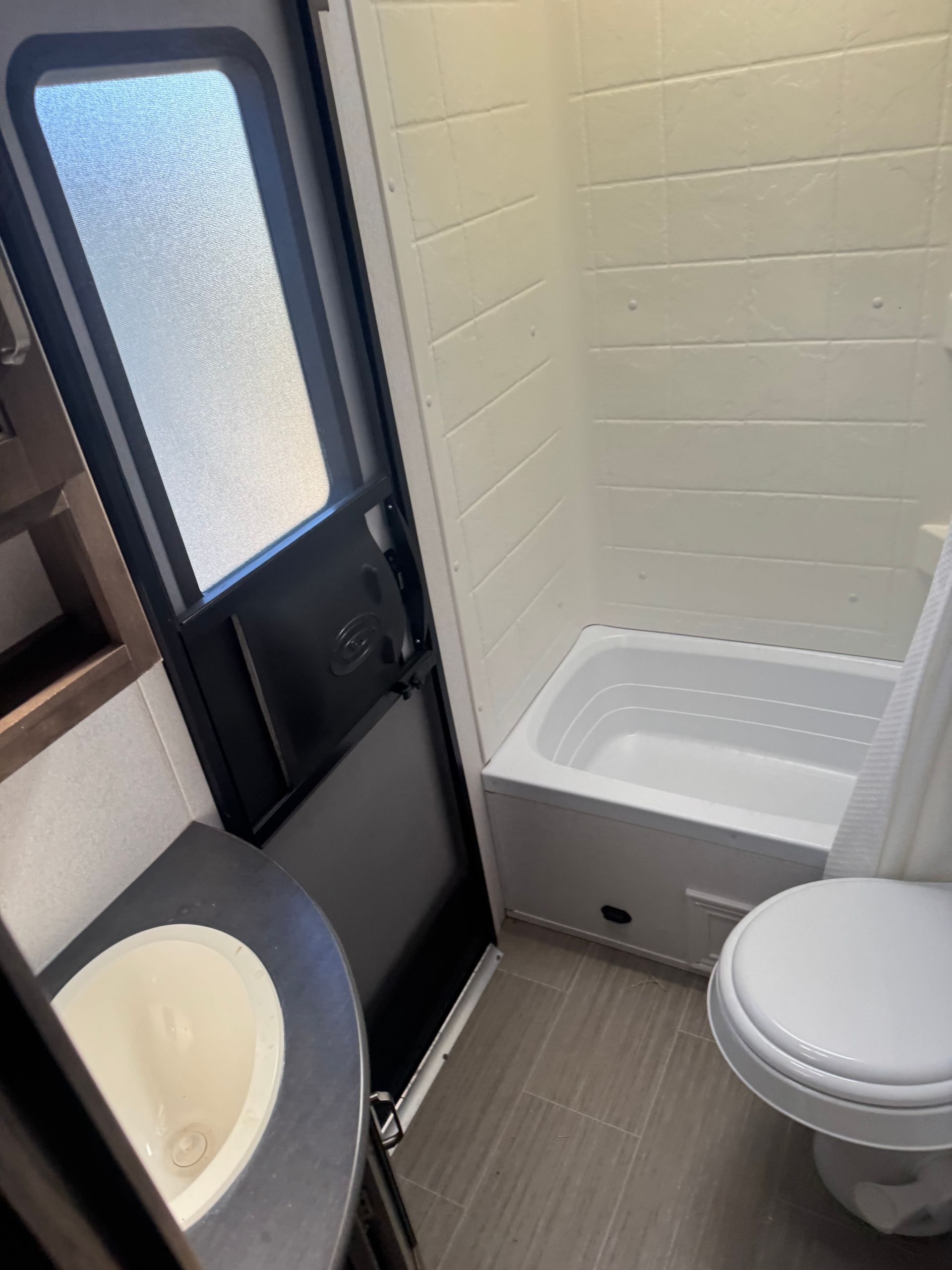 A bathroom with a toilet , sink and bathtub.