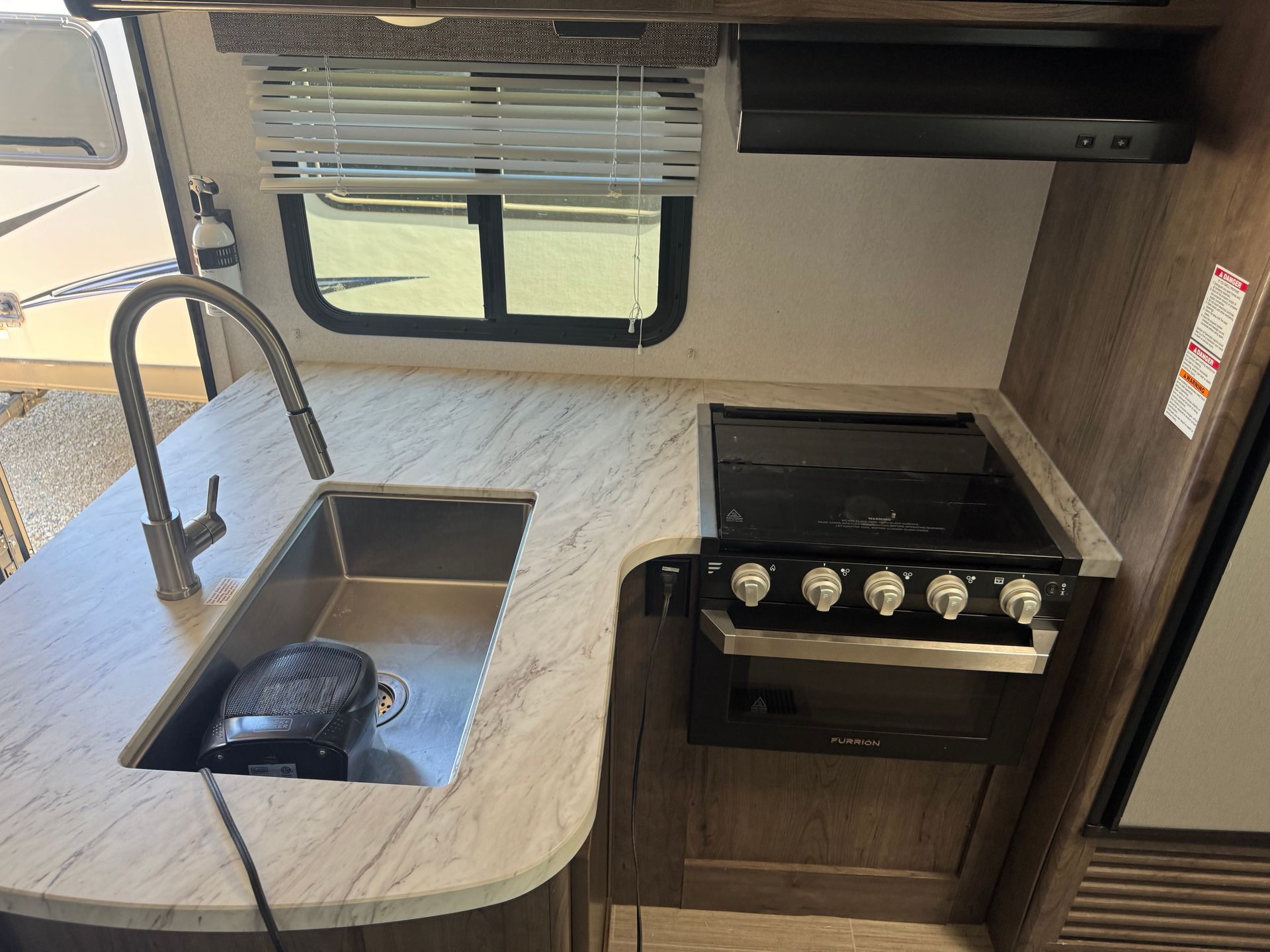 A kitchen in a rv with a sink , stove and oven.
