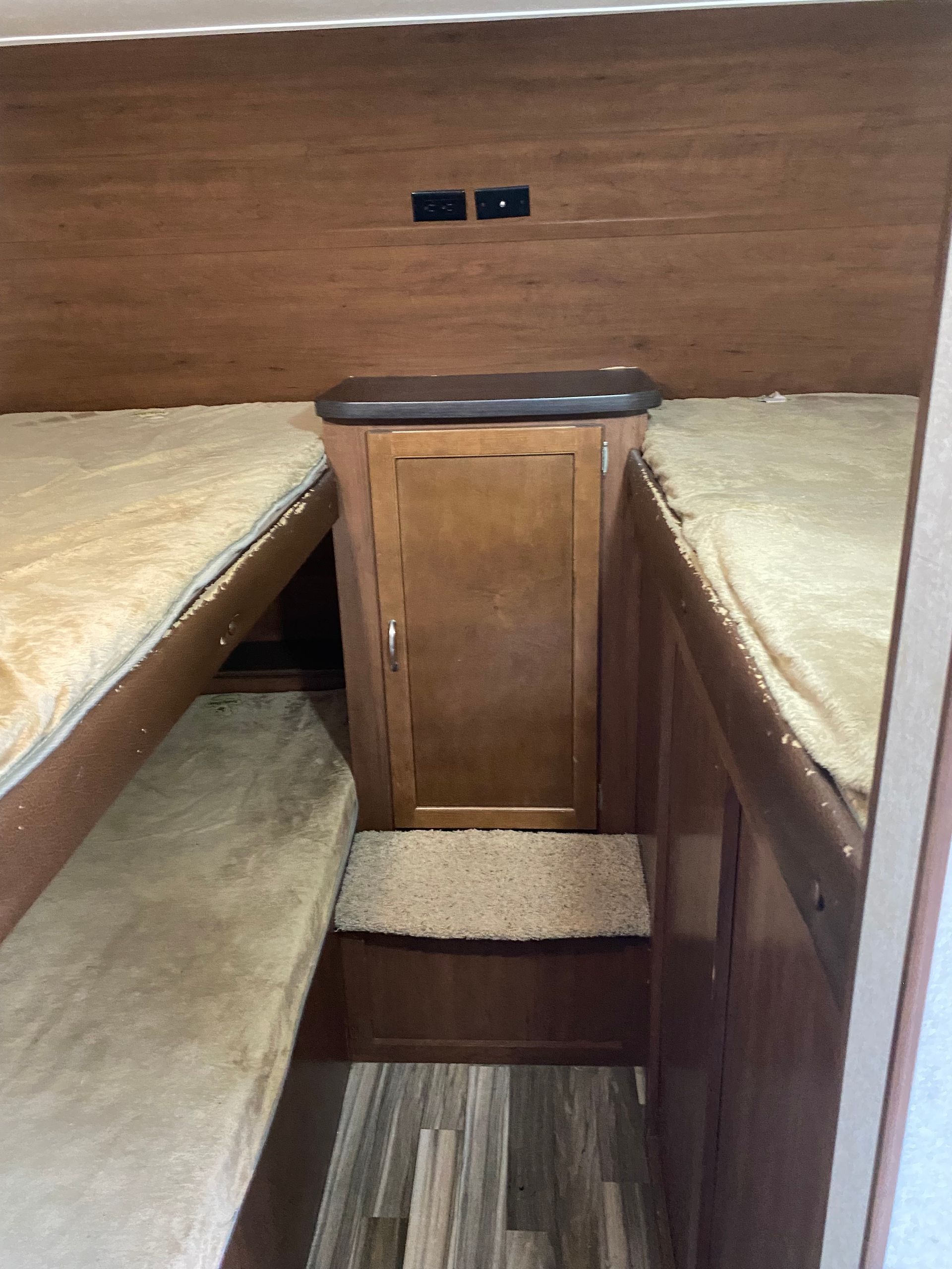 A room with bunk beds and a cabinet in a trailer.